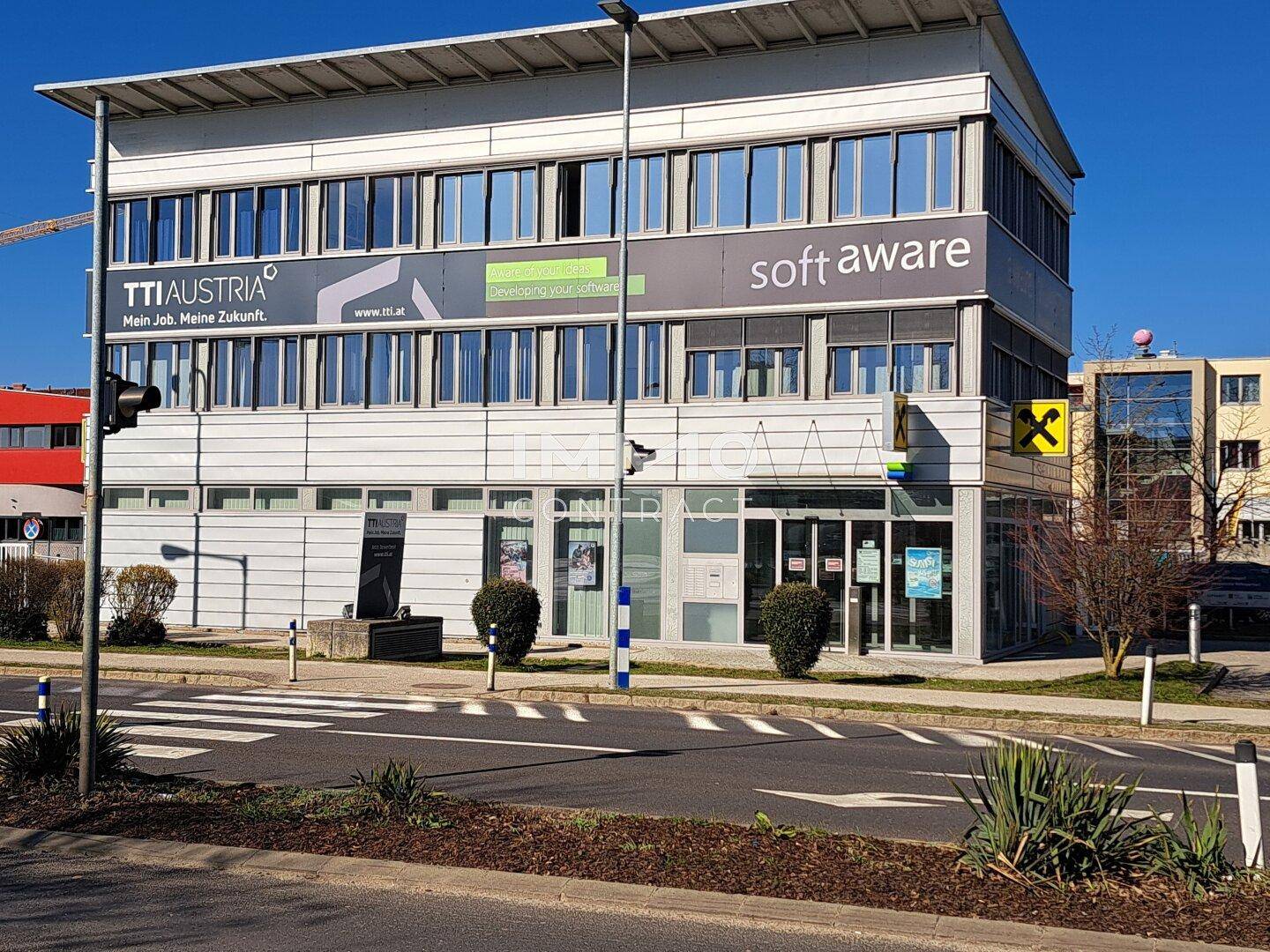 Modernes Geschäftsgebäude mit mehreren Etagen und großen Fensterfronten an einer Hauptstraße.