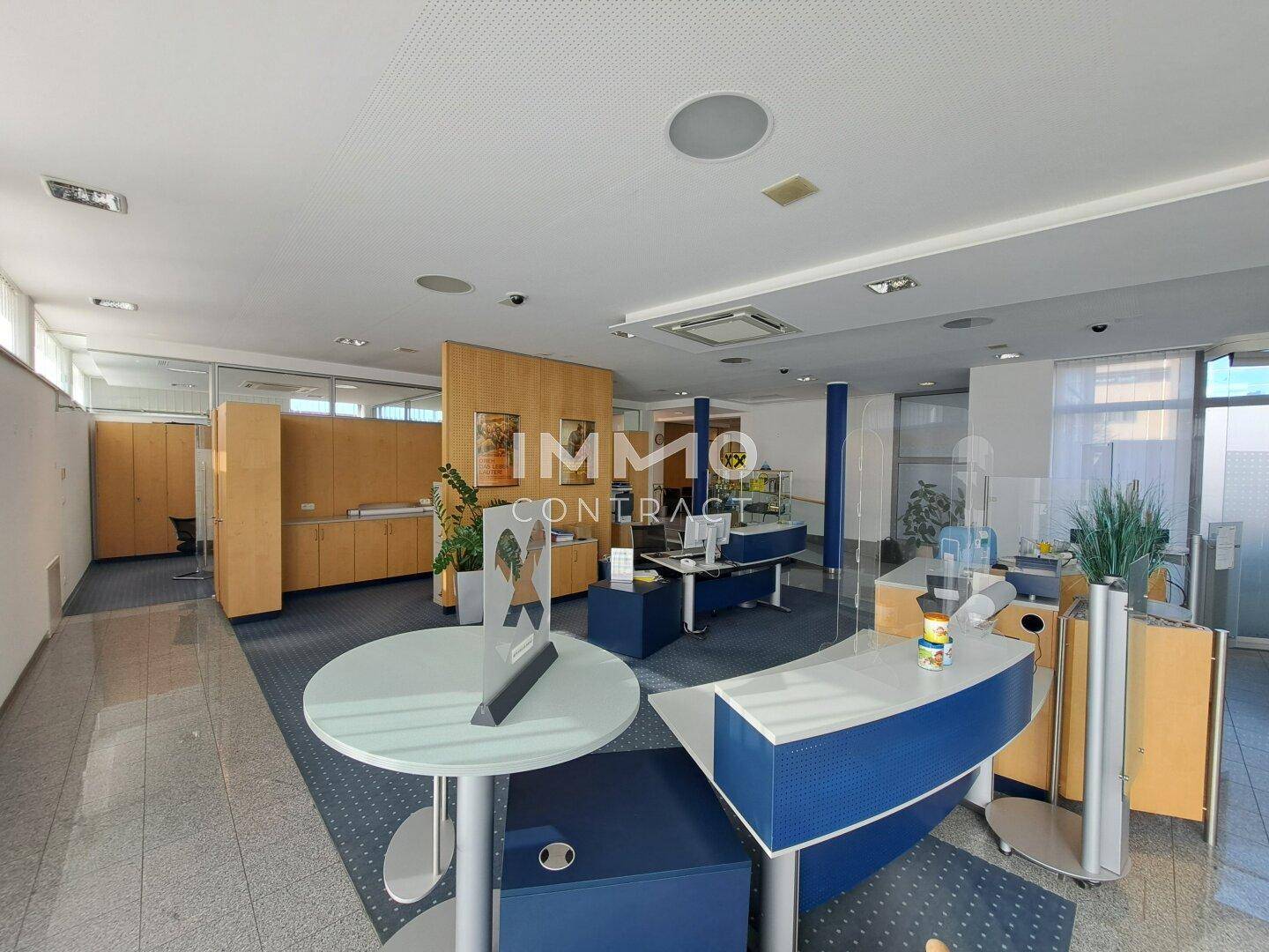 Offener Bürobereich mit Empfangstheke und verschiedenen Arbeitsplätzen, ausgestattet mit Teppichboden.