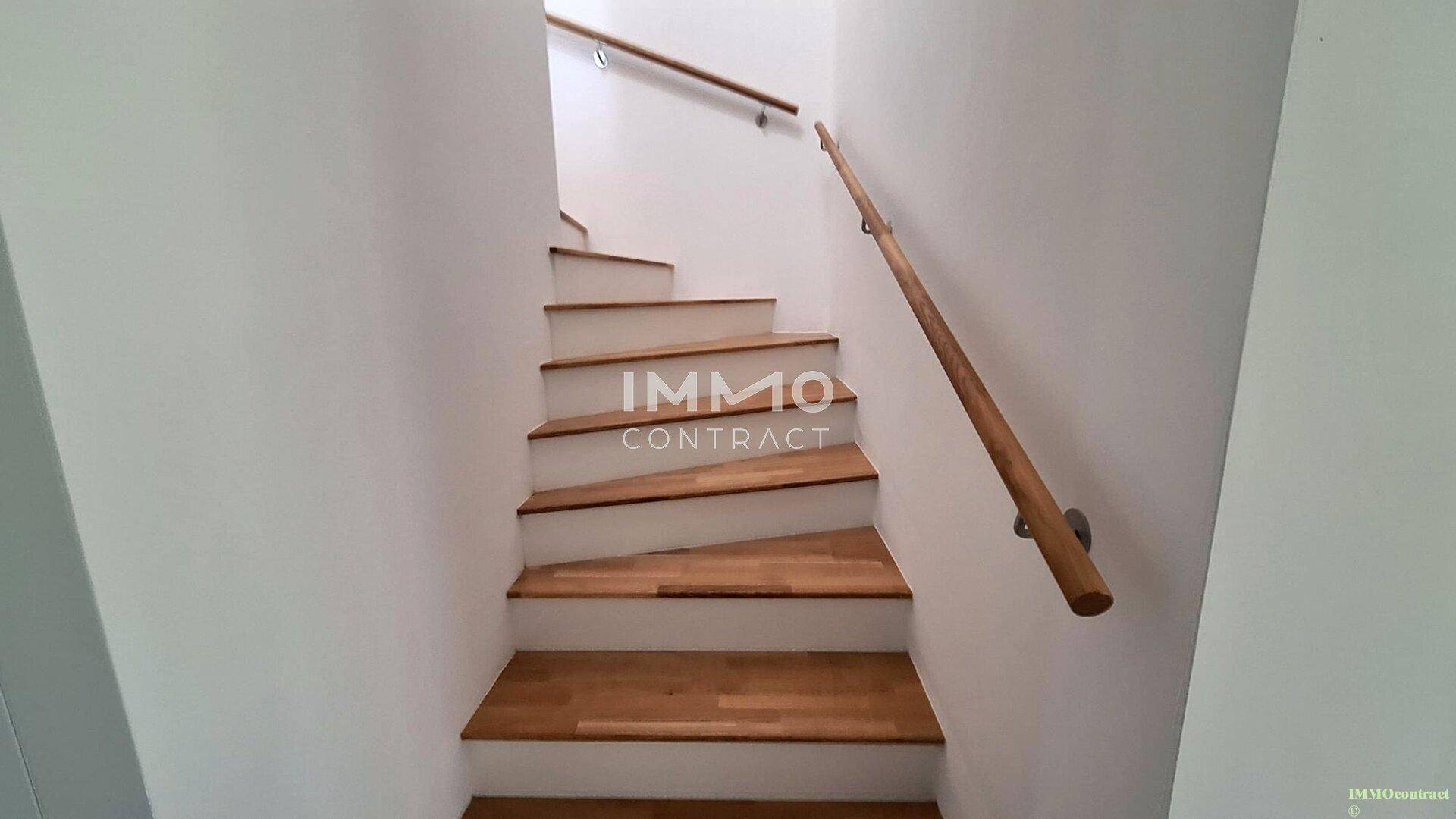 Holztreppe mit Geländer, die die verschiedenen Etagen des Hauses verbindet.