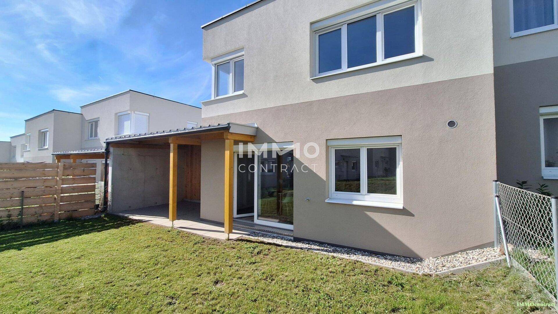 Rückseite eines modernen Reihenhauses mit überdachter Terrasse und Garten.