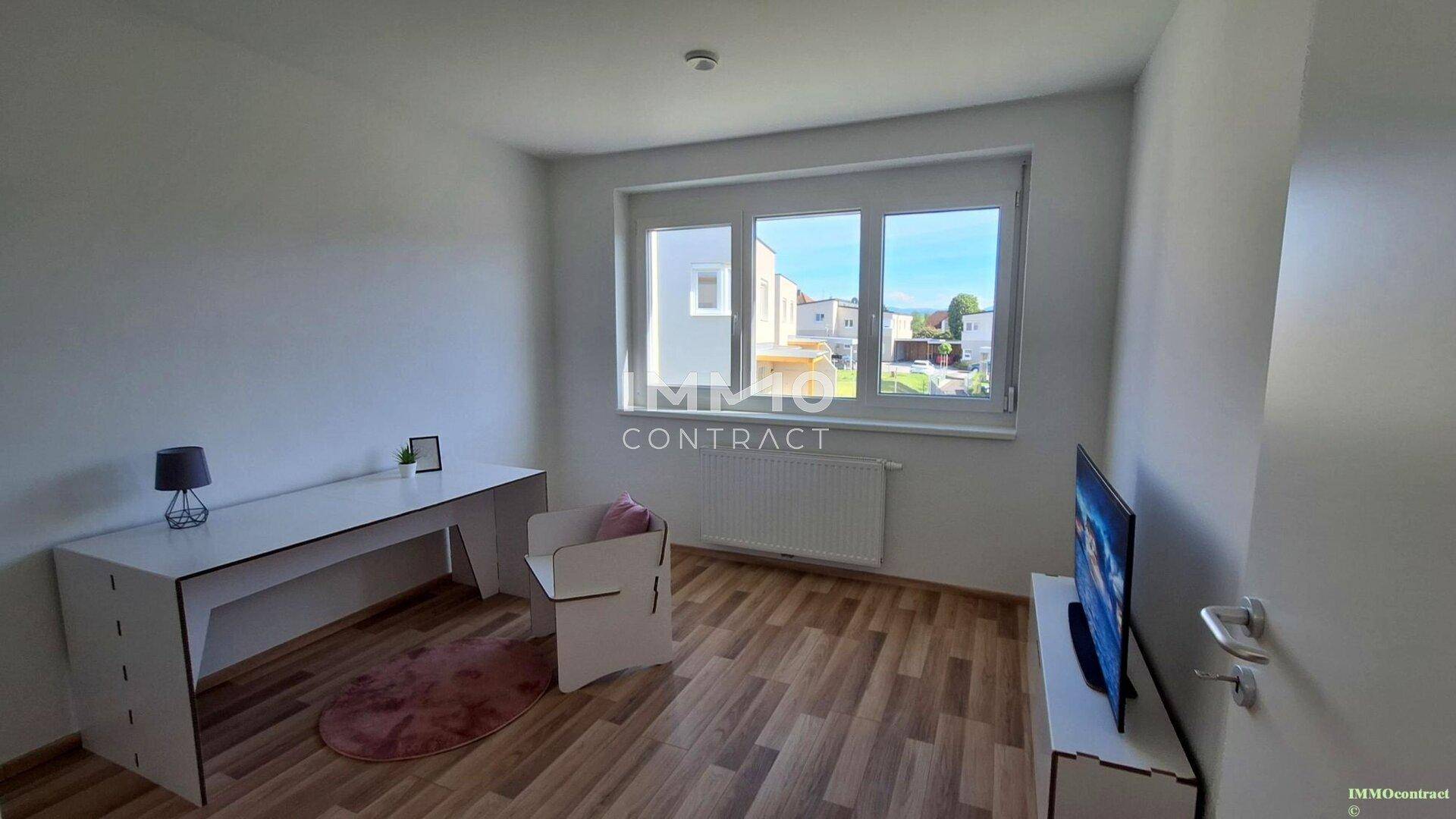 Arbeitszimmer mit Schreibtisch, Laminatboden und weitem Blick aus dem Fenster.
