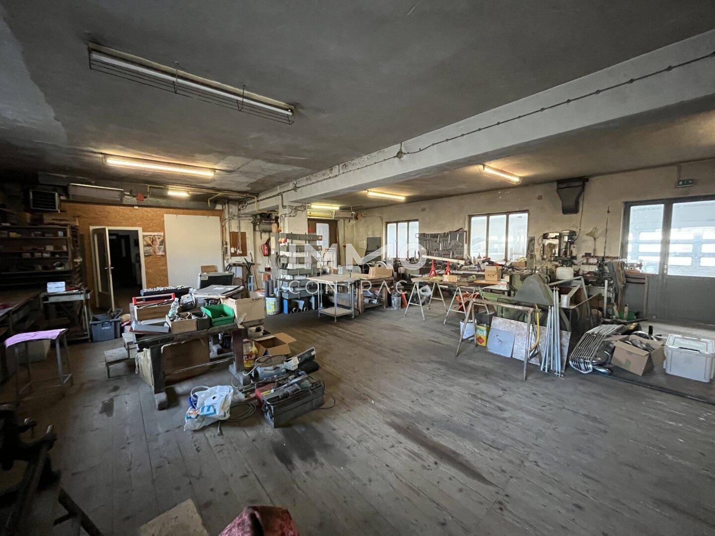 Geräumiger Werkstattbereich mit Holzboden, Fenstern und viel Platz für Arbeitsmaterialien.