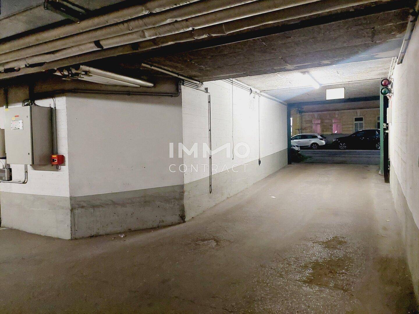 Einfahrt und Ausfahrt der Tiefgarage mit Blick auf die Straße und geparkte Autos im Freien.