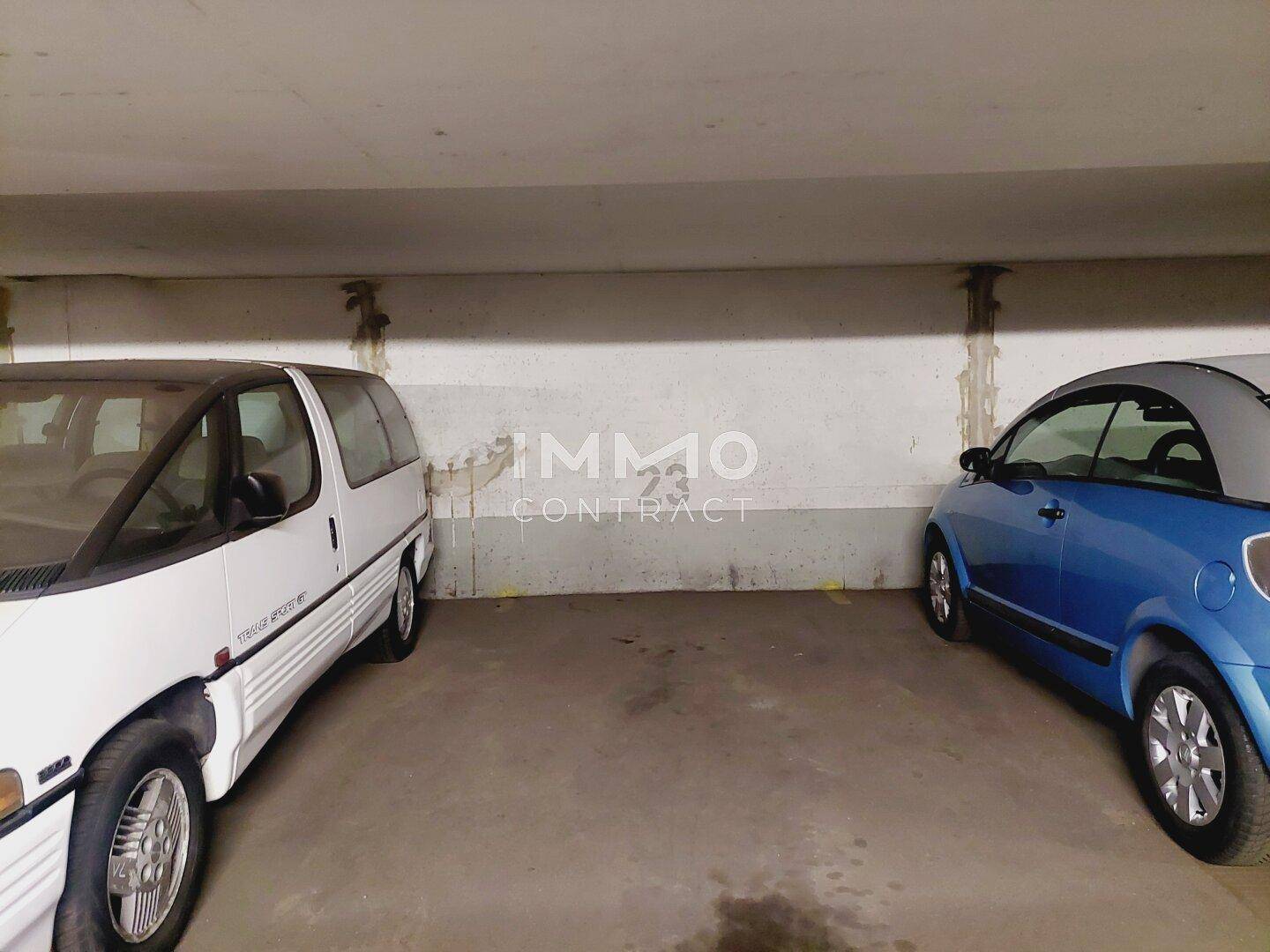 Parkplätze in der Tiefgarage mit geparkten Fahrzeugen und rauen Betonwänden im Hintergrund.