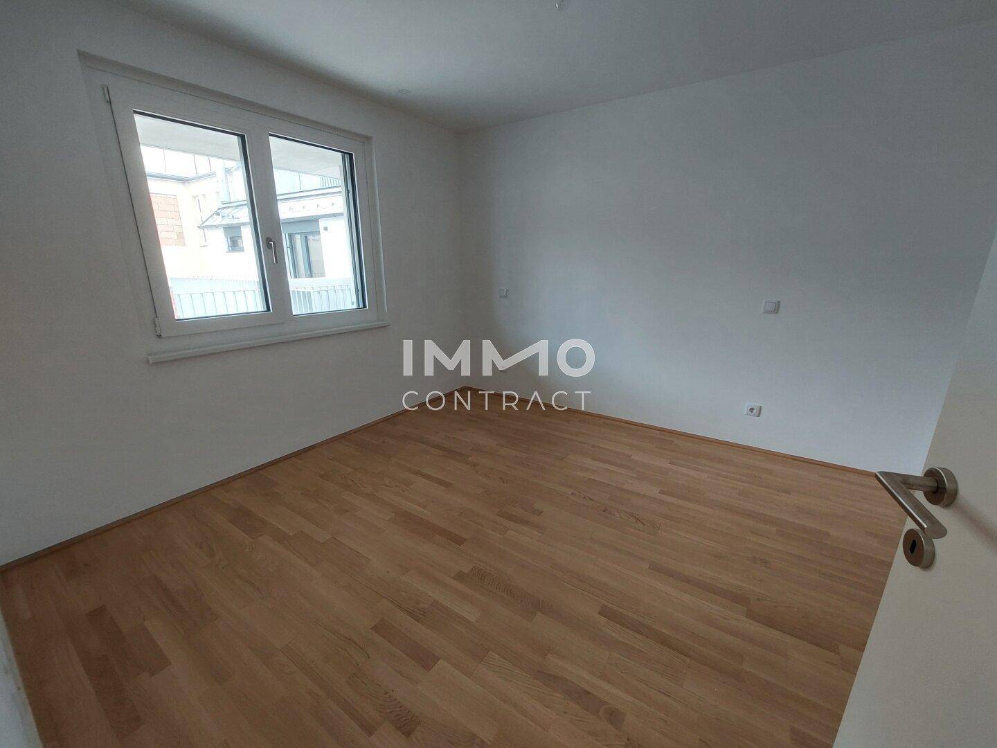Helles Zimmer mit Parkettboden und großem Fenster, ideal als Schlaf- oder Arbeitszimmer.