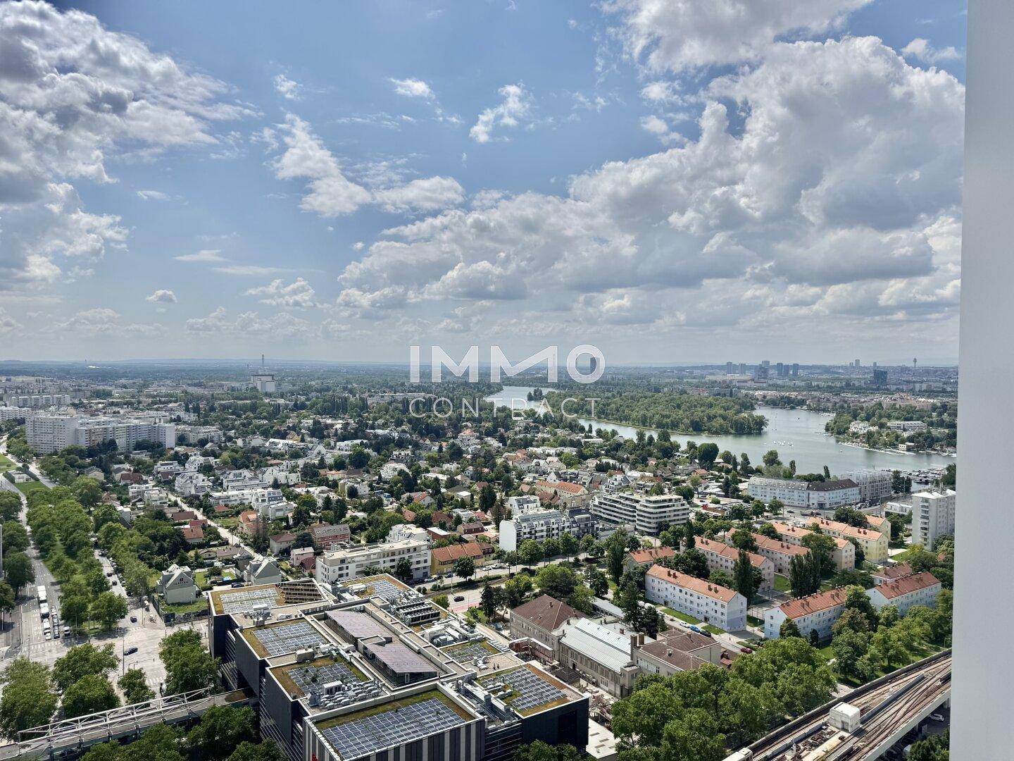 Panoramablick über die Stadt, den Fluss und die grüne Umgebung unter blauem Himmel.