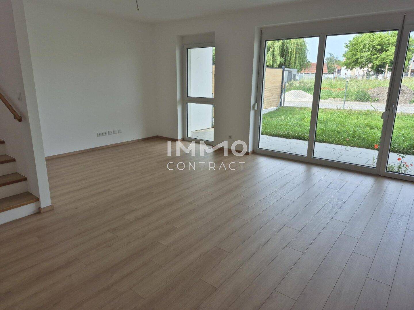 Heller Wohnbereich mit Laminatboden und großen Fenstern zum Garten.