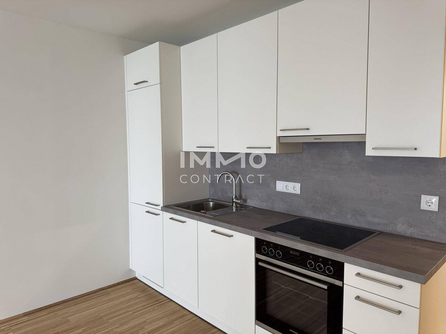 Moderne Einbauküche mit weißen Schränken und integrierten Geräten, funktional und stilvoll.