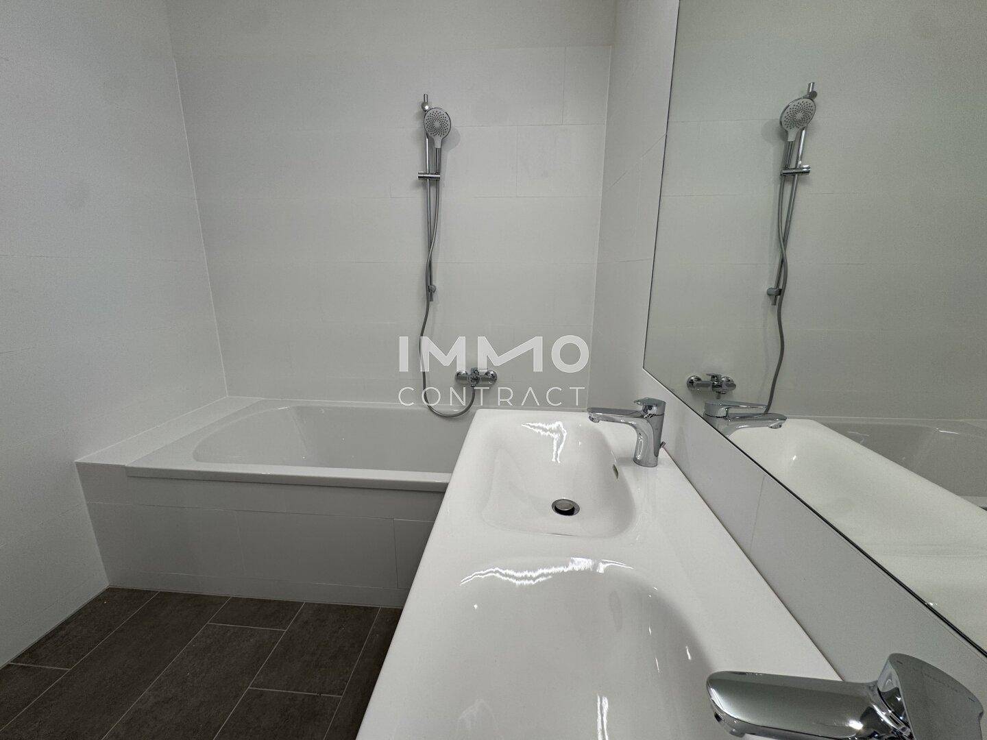Nahaufnahme des modernen Doppelwaschbeckens und der Badewanne im Badezimmer mit Fliesenboden.