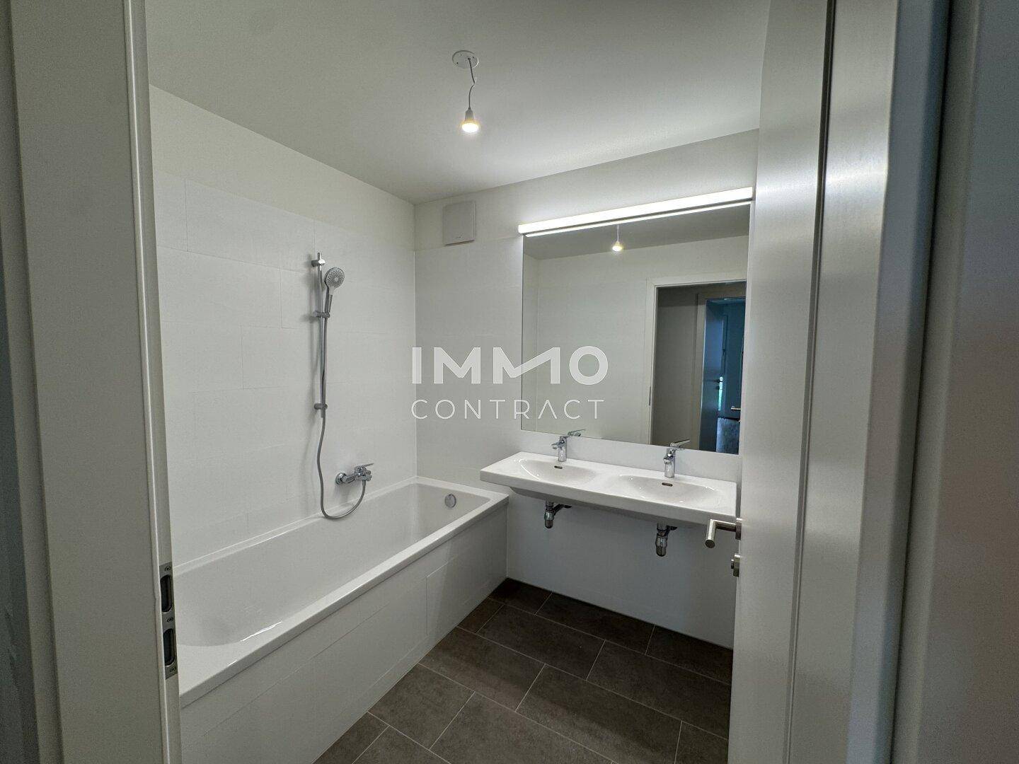 Modernes Badezimmer mit Badewanne, Doppelwaschbecken und großem Spiegel für Komfort.