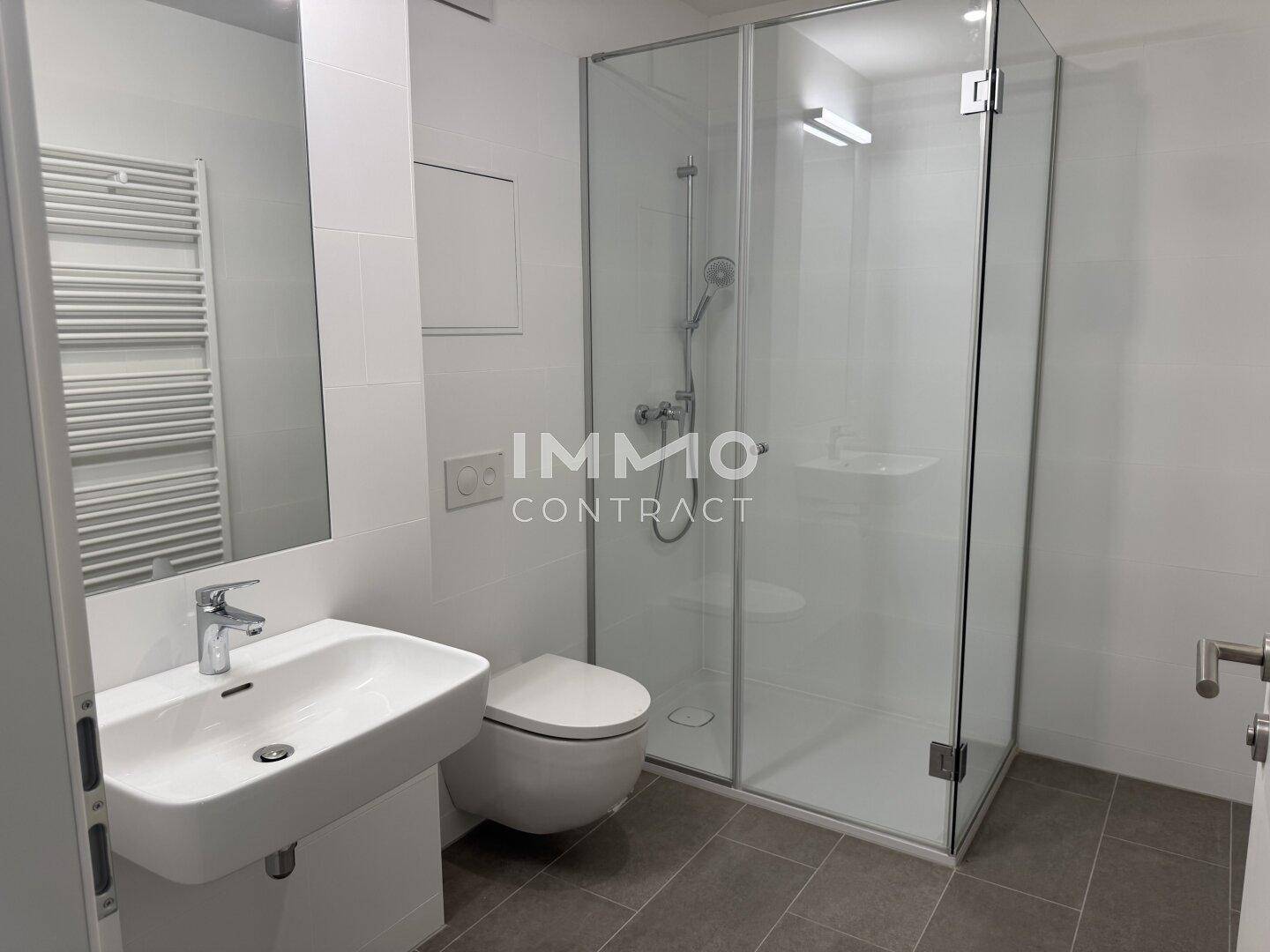 Modernes Badezimmer mit ebenerdiger Dusche, Wand-WC und beheiztem Handtuchhalter.