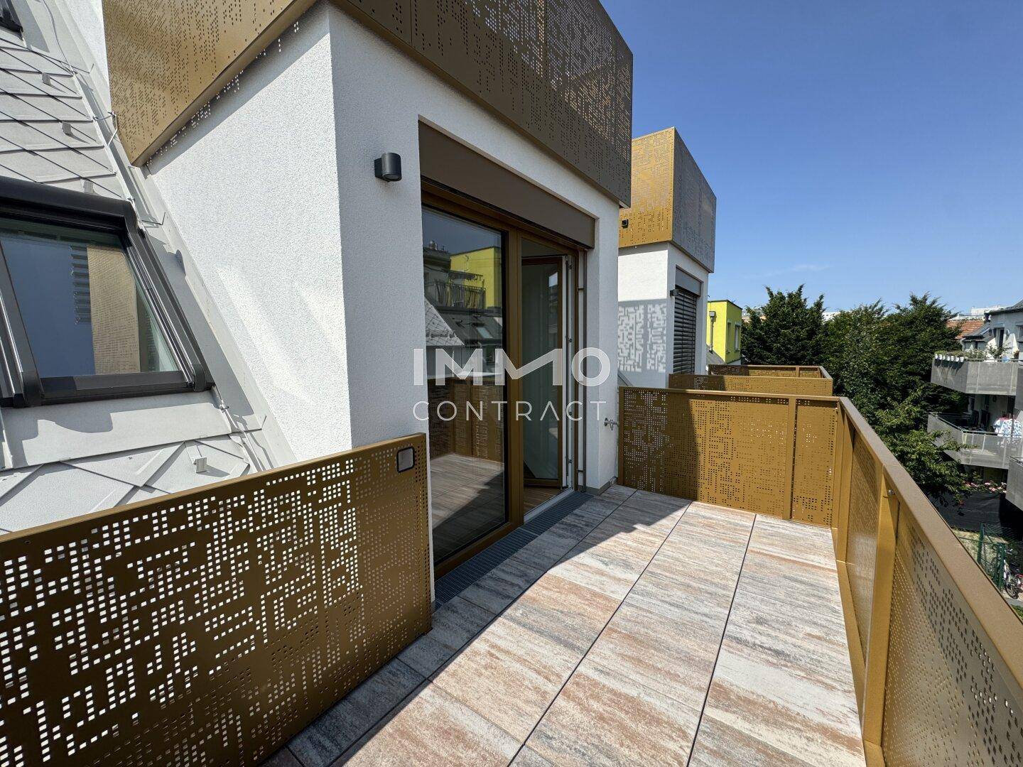 Heller Balkon mit modernen perforierten Metallgeländern und Fliesenboden unter blauem Himmel.