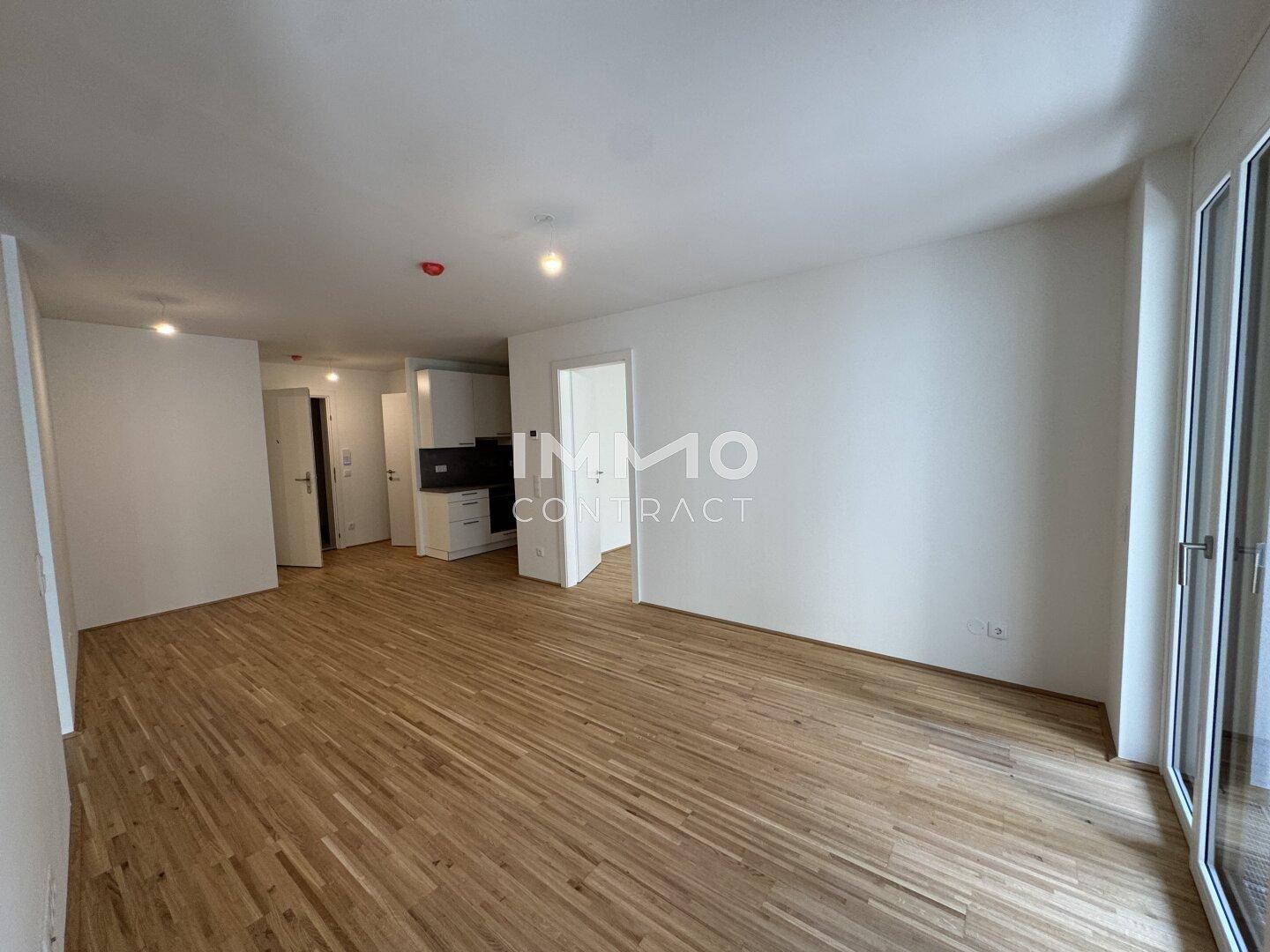Heller Wohnbereich mit Parkettboden und Zugang zu einem Balkon, ideal für offenes Wohnen.