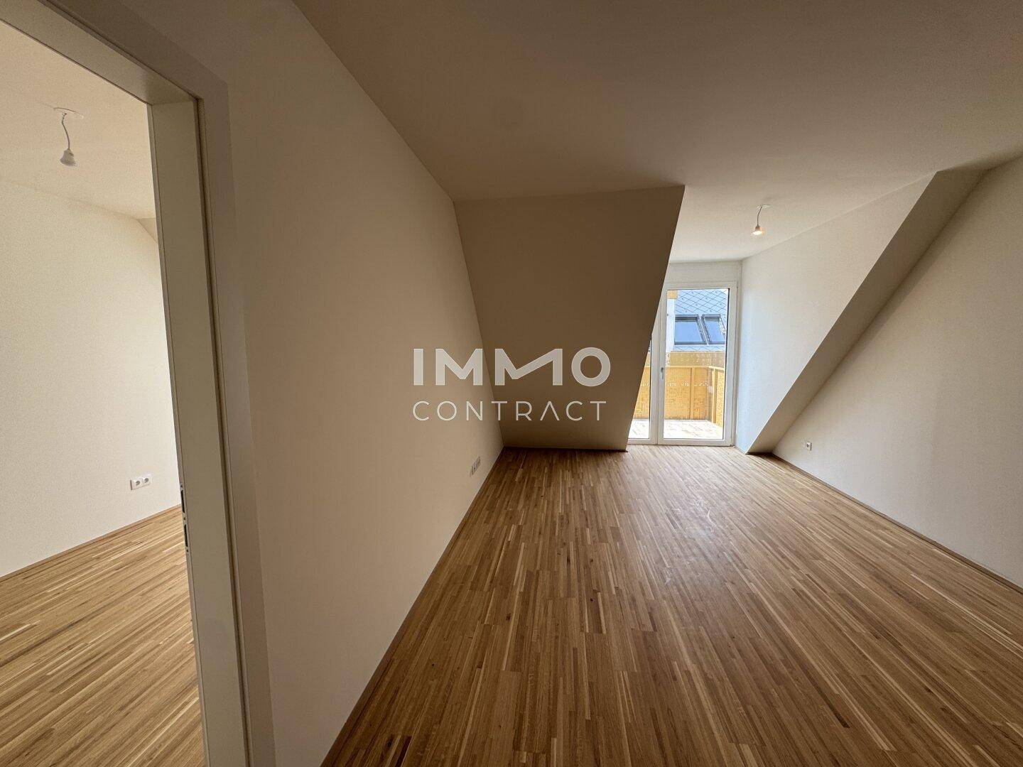 Lichtdurchfluteter Wohnbereich mit Parkettboden, Dachschrägen und Zugang zum Balkon.