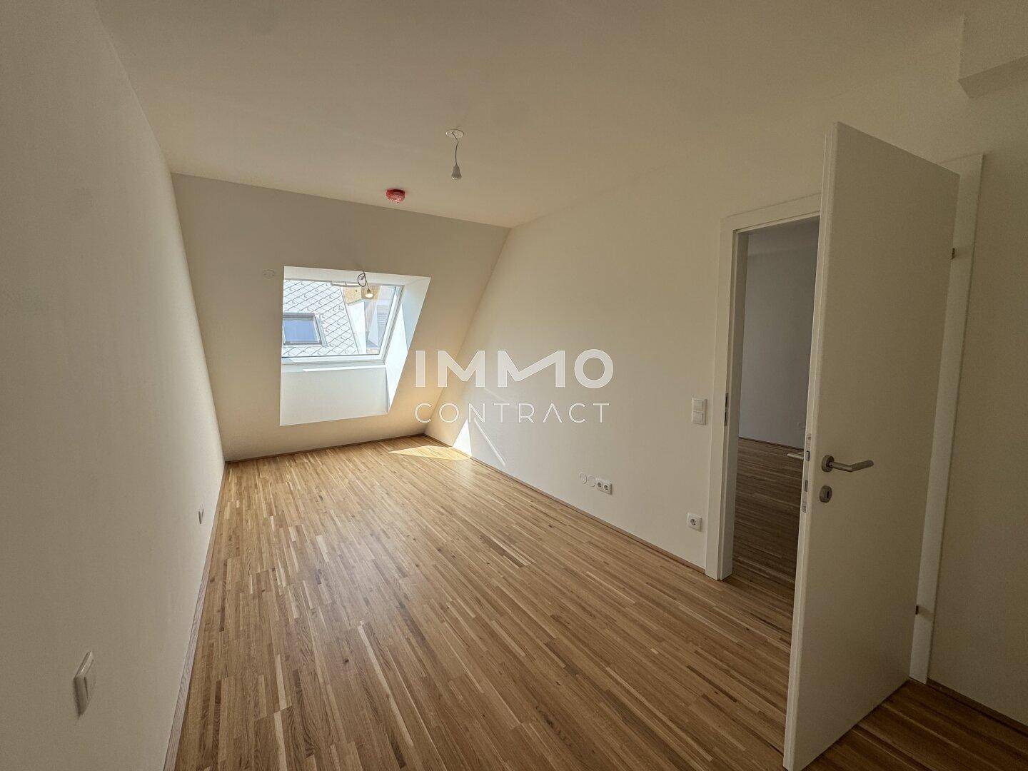 Helles Zimmer mit Parkettboden, Dachschräge und einem Dachfenster für viel Tageslicht.
