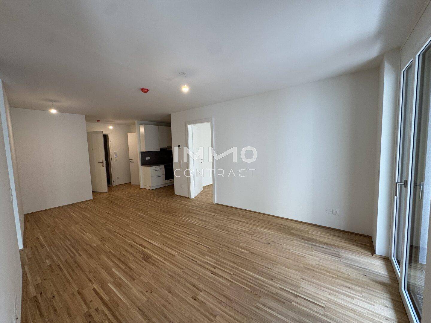 Heller Wohnbereich mit Parkettboden und Zugang zu einem Balkon, ideal für offenes Wohnen.