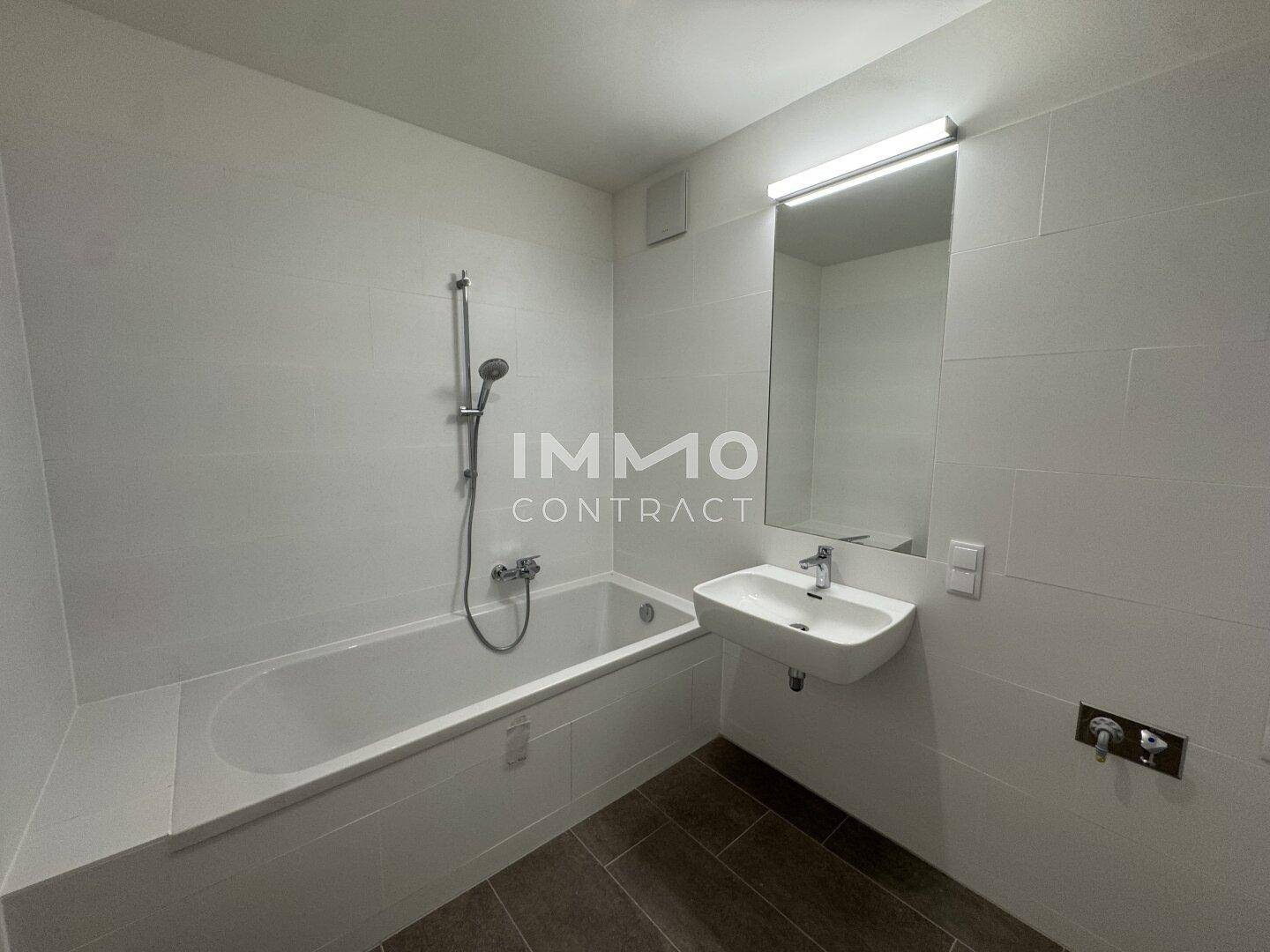Modernes Badezimmer mit weiß gefliesten Wänden, Badewanne und Einzelwaschbecken.