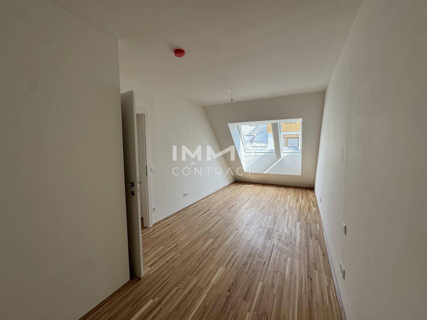 Helles Schlafzimmer mit Parkettboden und Dachfenster, bietet eine gemütliche Atmosphäre.