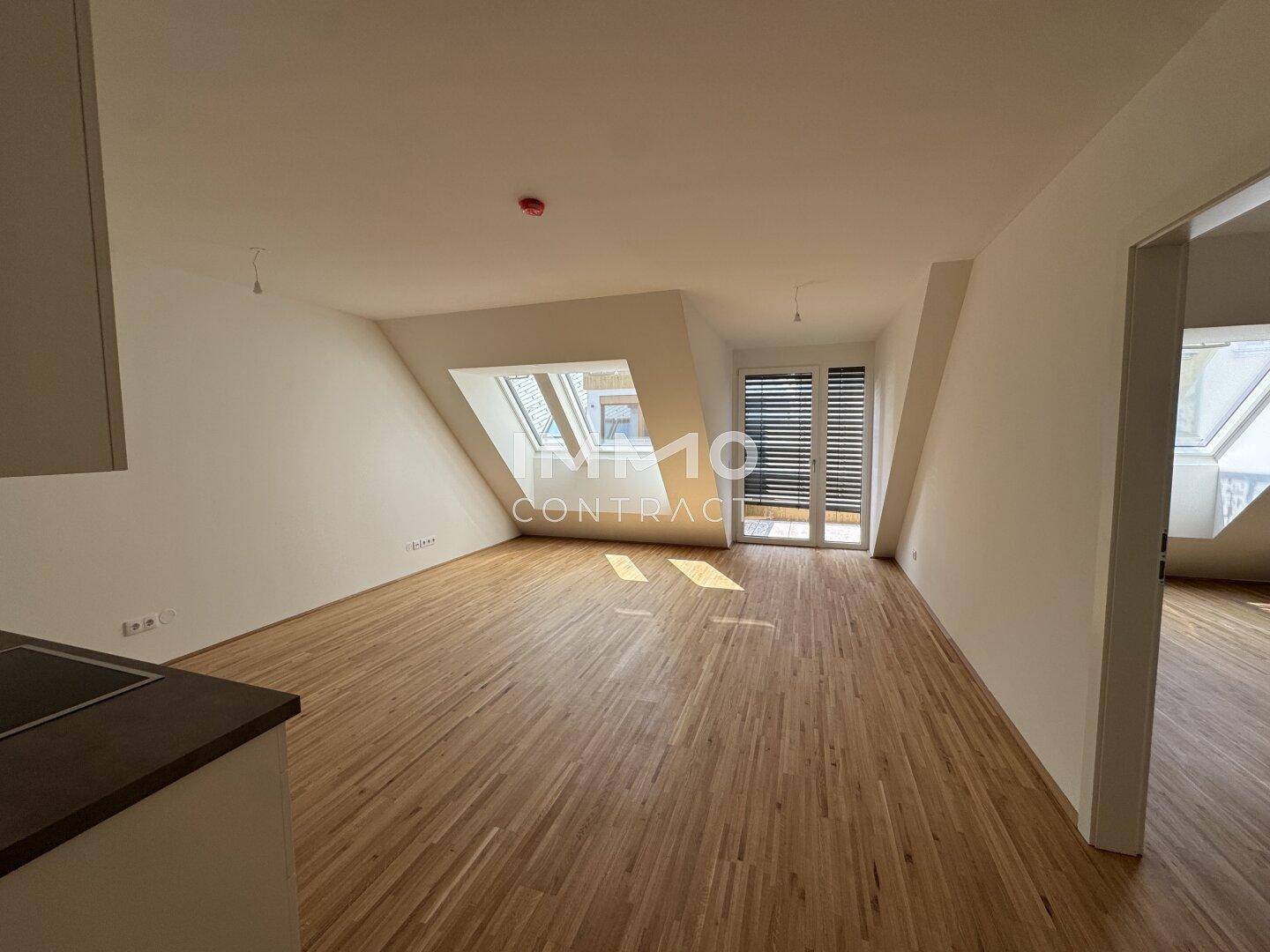 Heller Dachgeschossraum mit schrägen Wänden, Parkettboden und mehreren Dachfenstern für viel Licht.