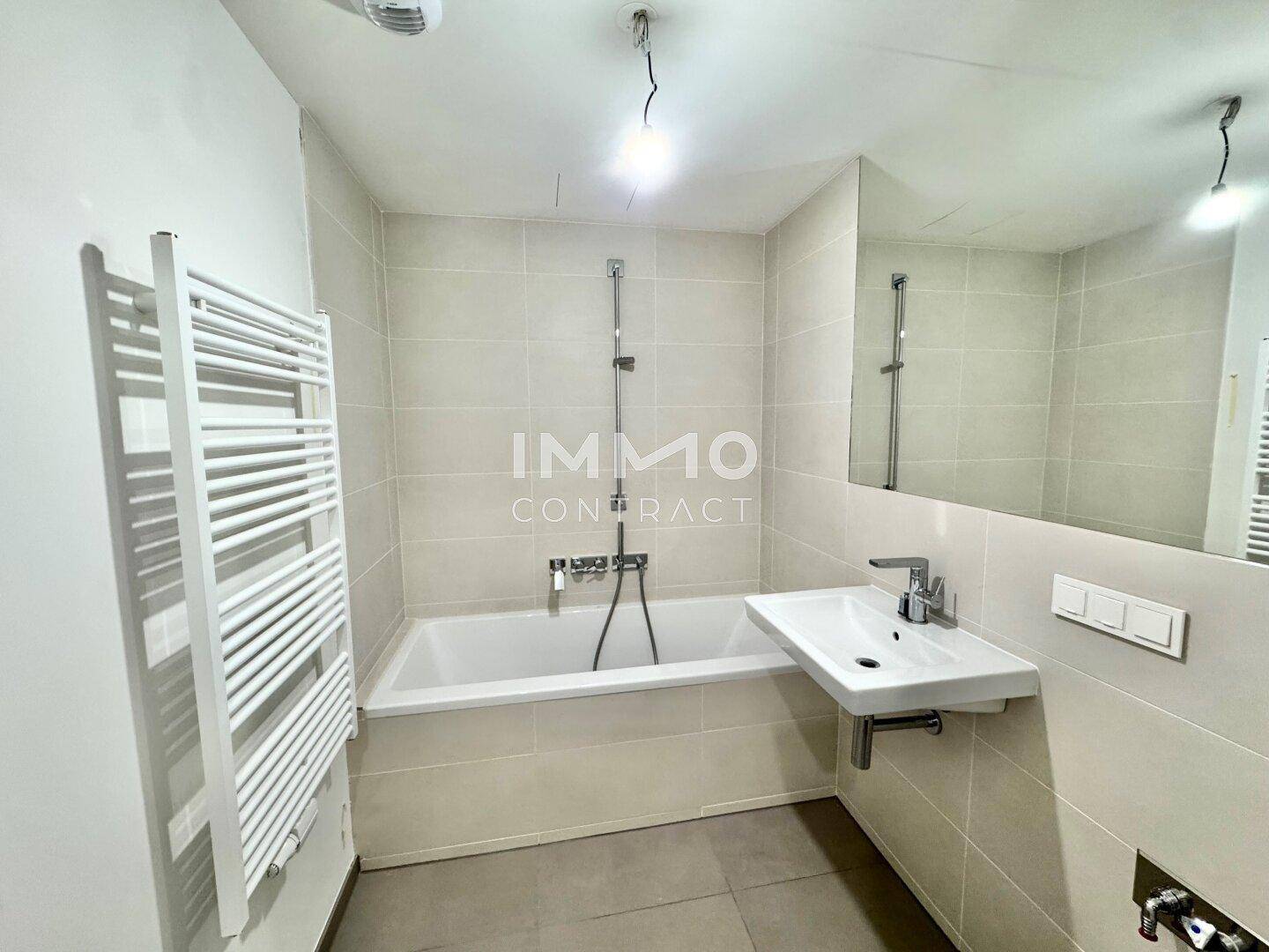 Modernes Badezimmer mit Badewanne, Waschbecken und beheiztem Handtuchhalter.