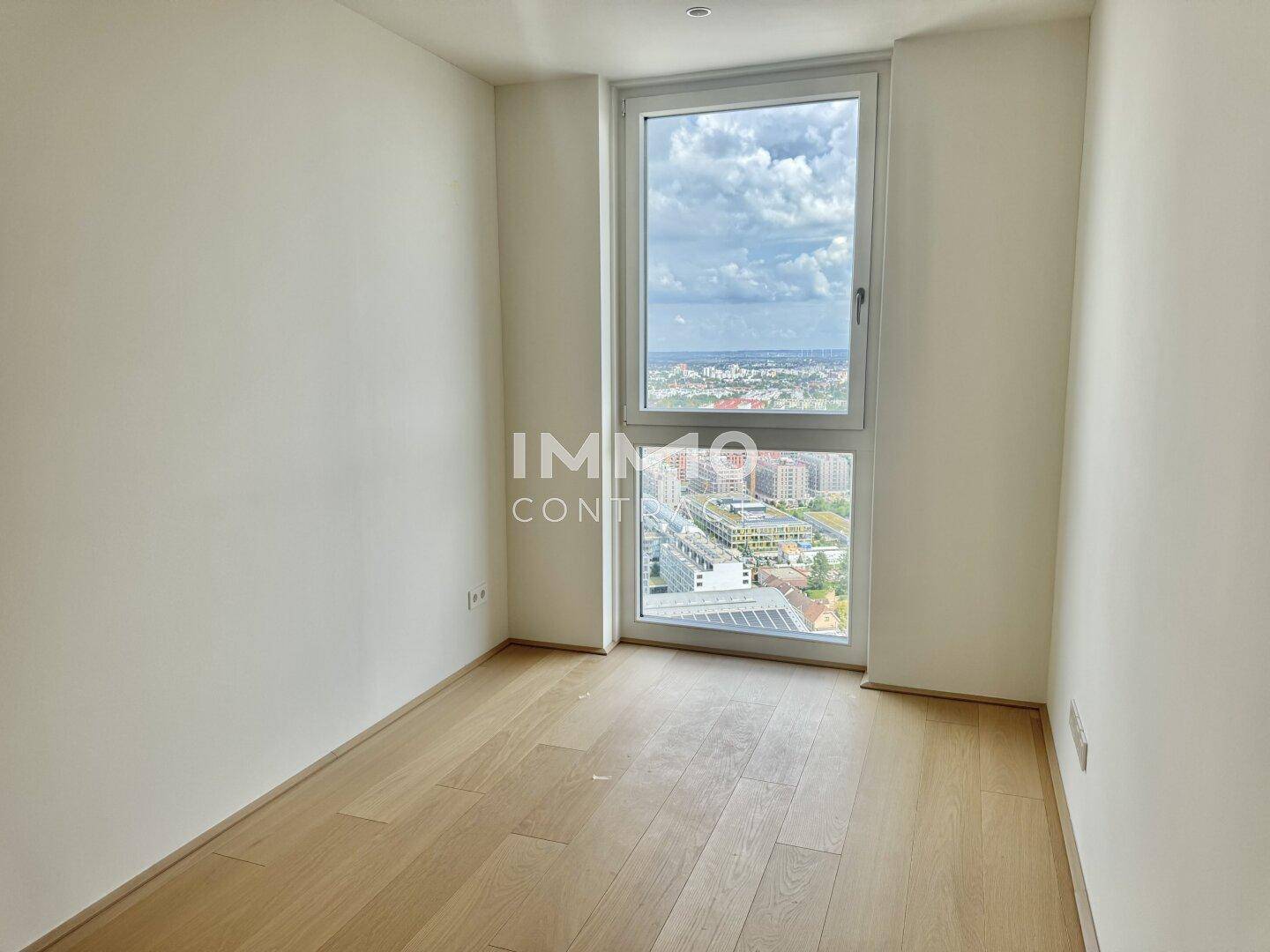Helles Schlafzimmer mit Parkettboden und Fenster mit weitem Ausblick.