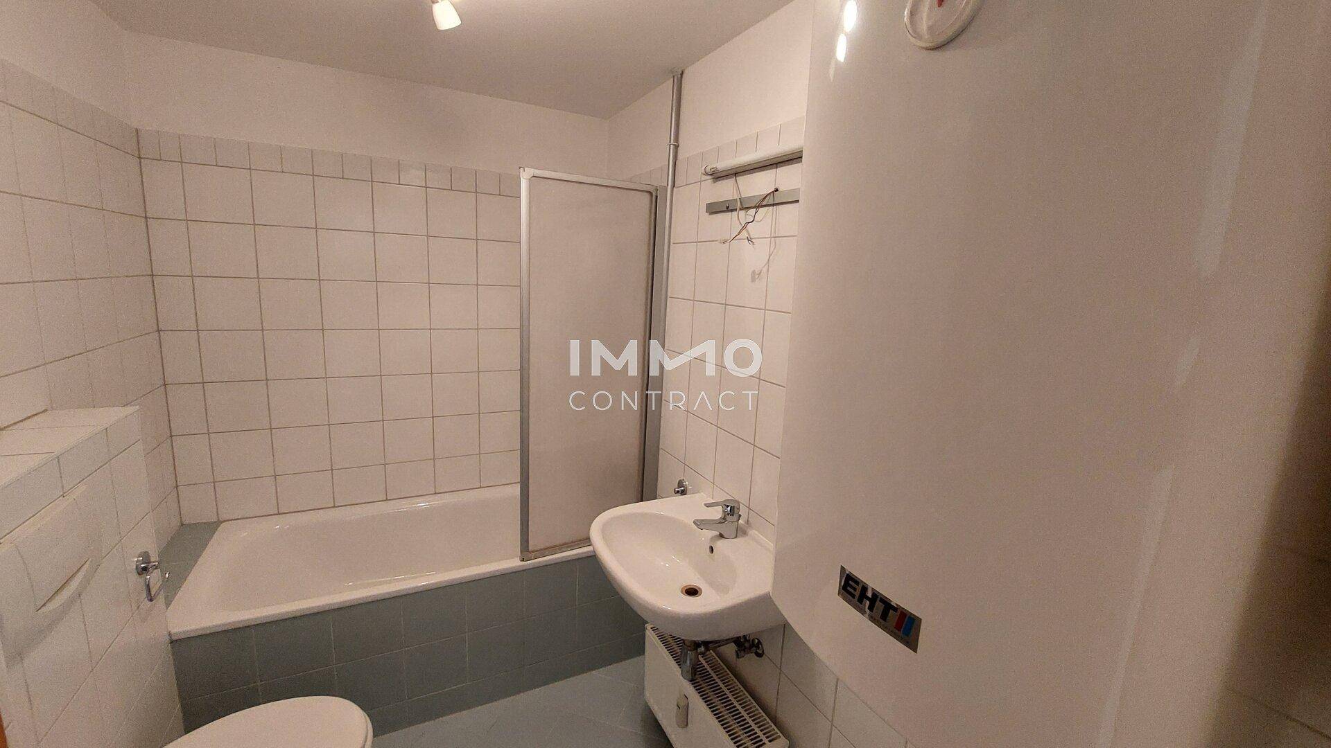 Badezimmer mit Badewanne, Duschabtrennung, Waschbecken und Boiler.