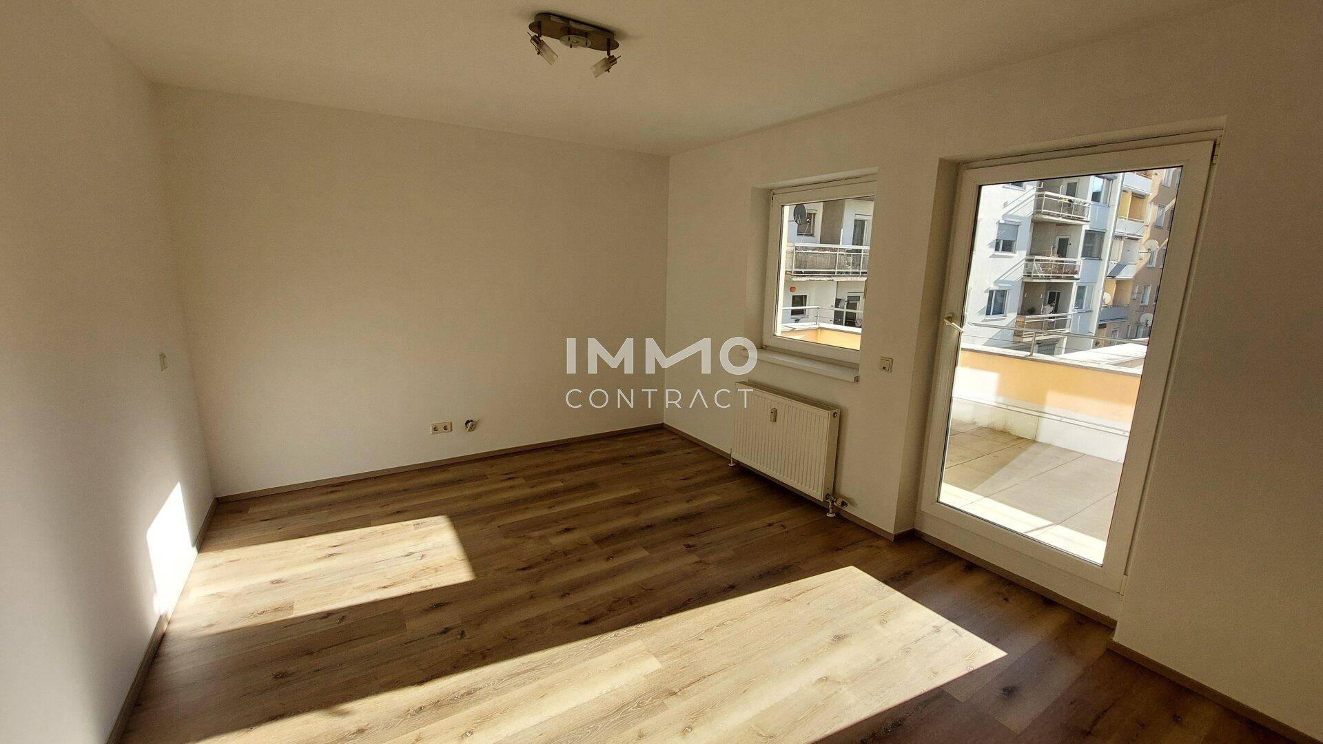 Heller Raum mit Laminatboden und Zugang zu einer Terrasse, ideal als Wohnzimmer.