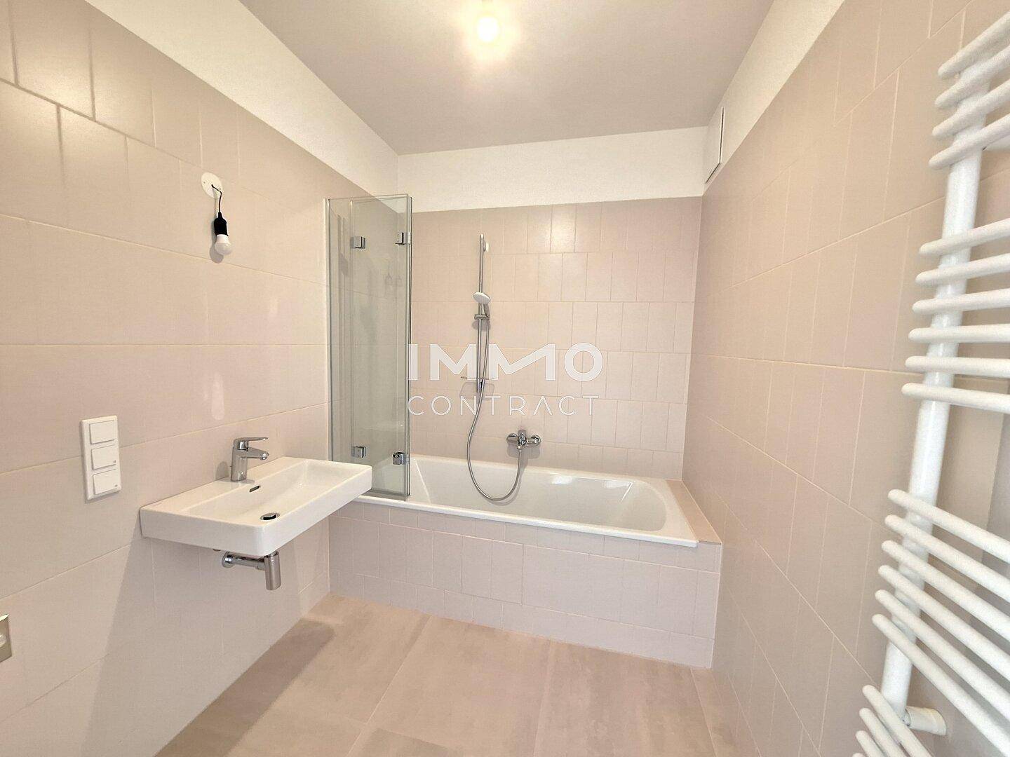 Modernes Badezimmer mit Badewanne, Duschabtrennung und beheiztem Handtuchhalter.