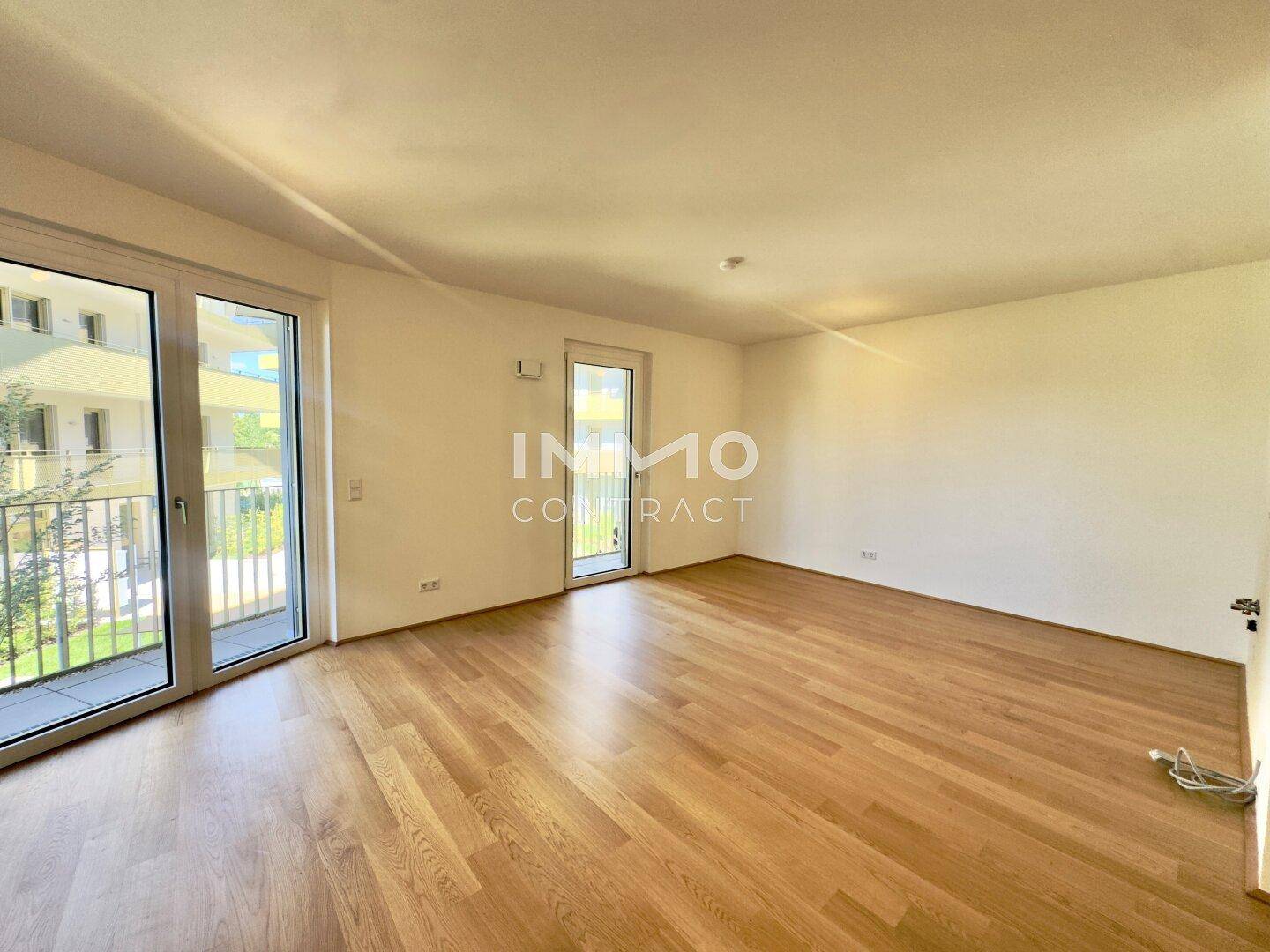Geräumiger, heller Raum mit großen Fenstern und Zugang zu einem Balkon, ideal für Wohnzwecke.
