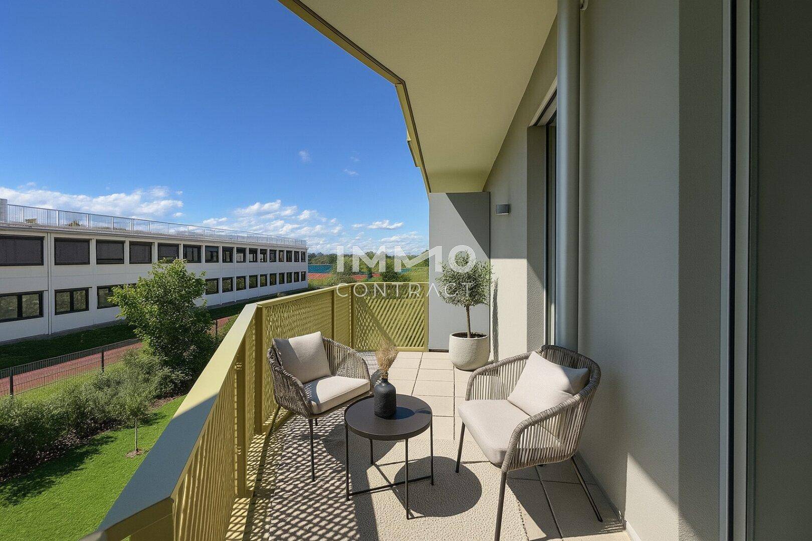 Möblierter Balkon mit Blick auf eine Grünfläche und angrenzende Gebäude.
