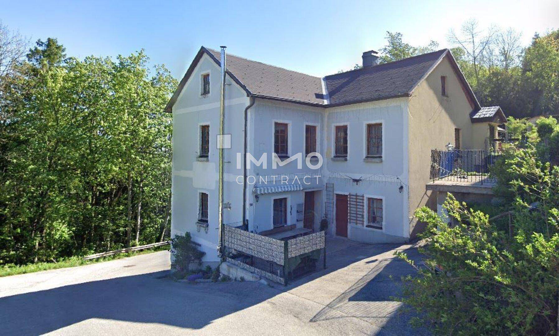 Traditionelles Haus mit hellblauer Fassade und Satteldach, umgeben von viel Grün.