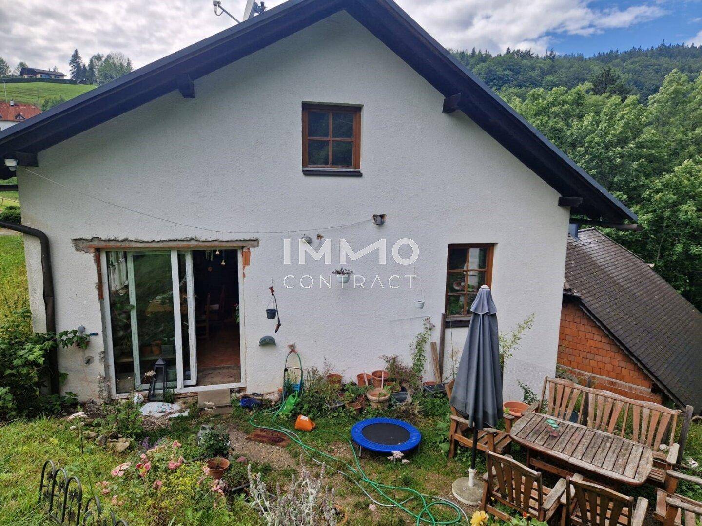 Hinterhof mit Gartenbereich, Sitzgelegenheiten und Blick auf die umliegende Natur.