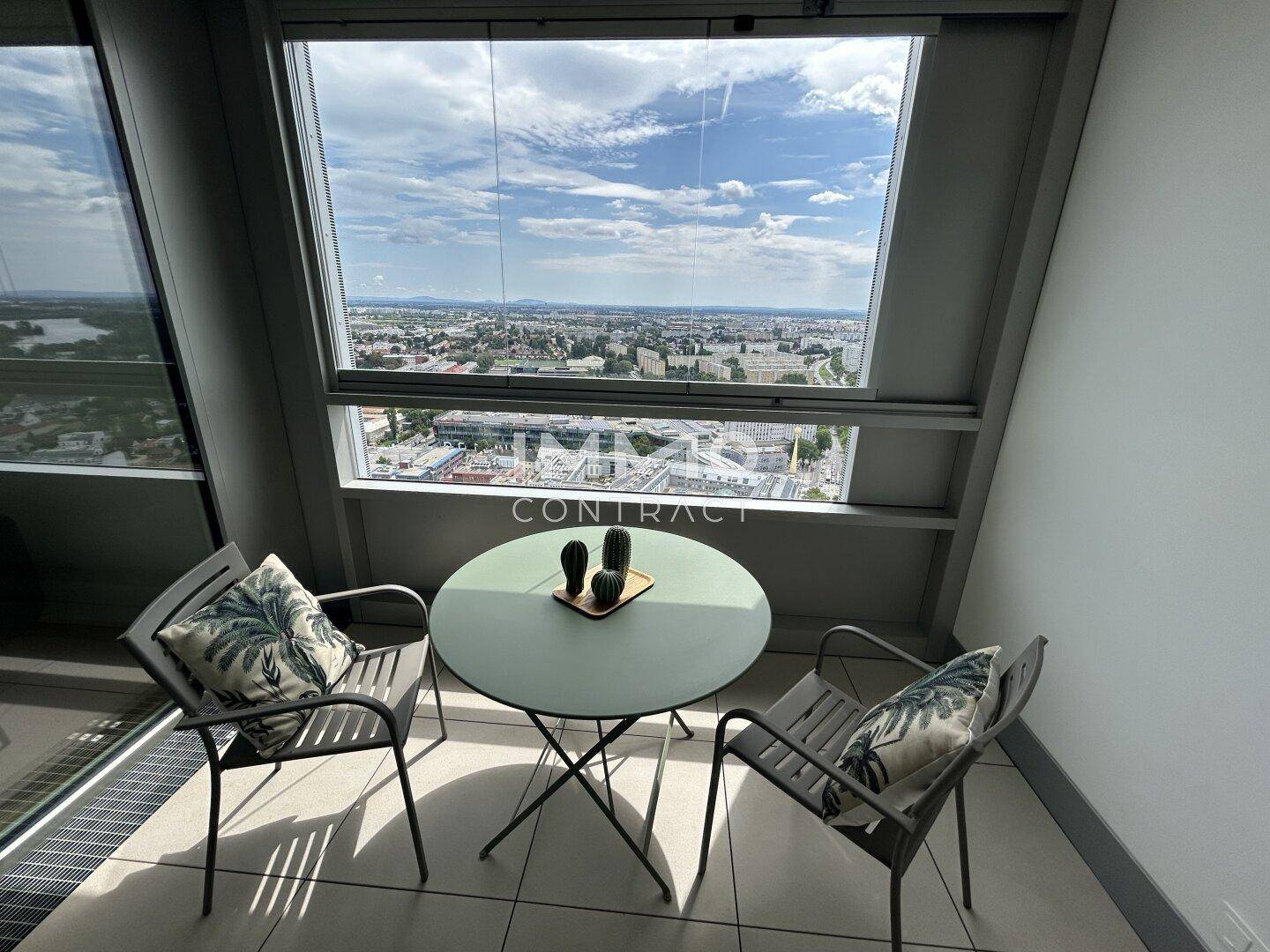 Gemütlicher verglaster Balkon mit Sitzgelegenheiten und einem weiten Blick über die Stadtlandschaft.
