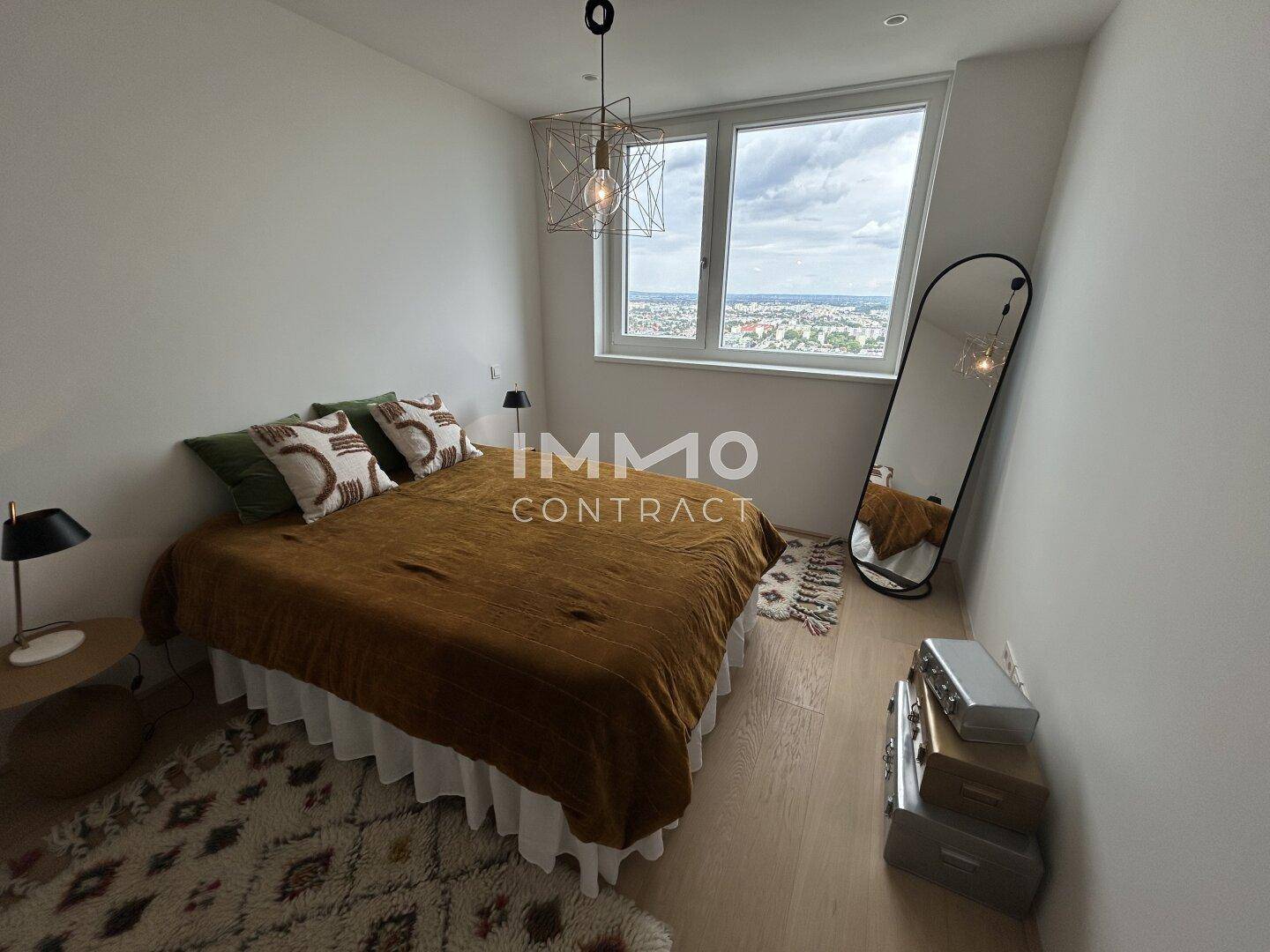 Gemütliches Schlafzimmer mit Holzboden, großem Fenster und einem Ganzkörperspiegel, bietet einen schönen Ausblick.