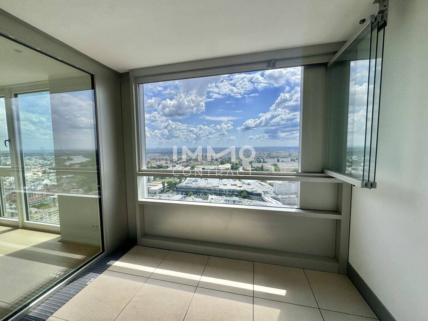 Heller, verglaster Balkon mit Fliesenboden und einem weiten Panoramablick über die Stadt.