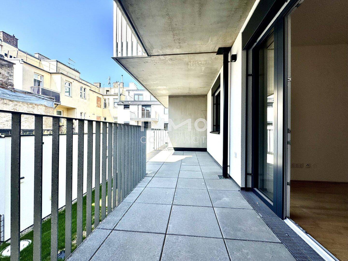 Geräumiger Balkon mit Fliesenboden und Blick auf die umliegenden Gebäude.