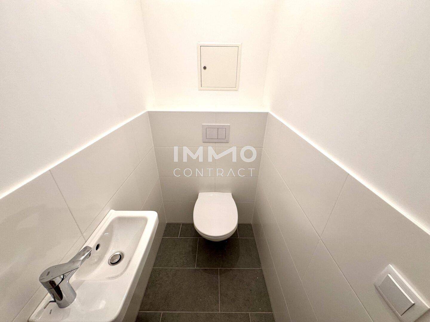 Separates Gäste-WC mit Wand-WC und kleinem Handwaschbecken.