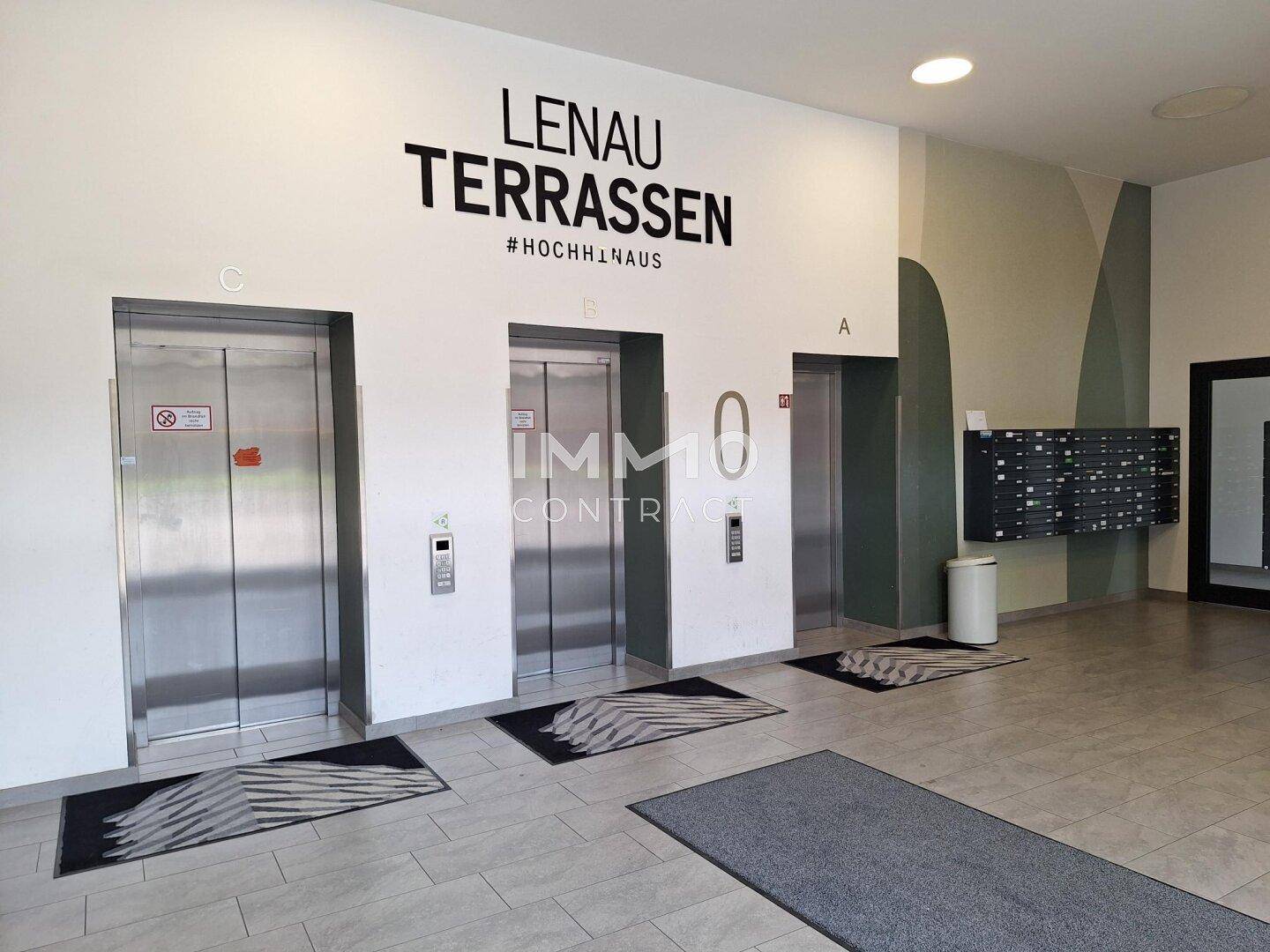 Moderner Eingangsbereich mit mehreren Aufzügen und Briefkästen in einem Wohngebäude.