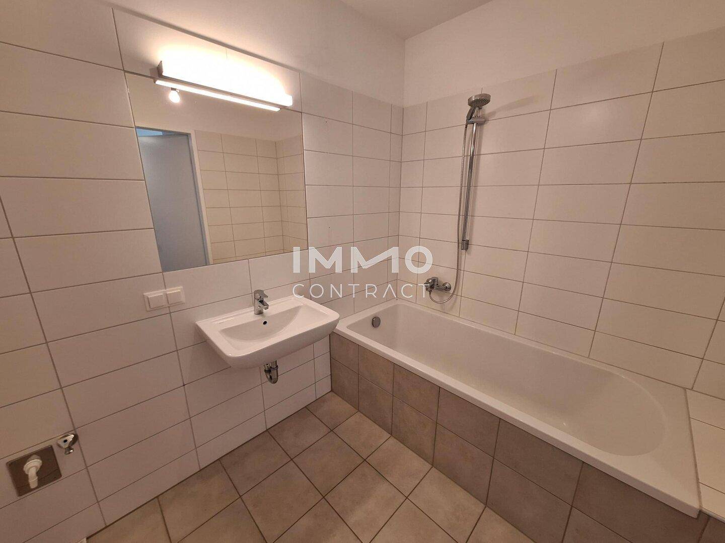 Modernes Badezimmer mit Badewanne, Waschbecken und weißen Wandfliesen.