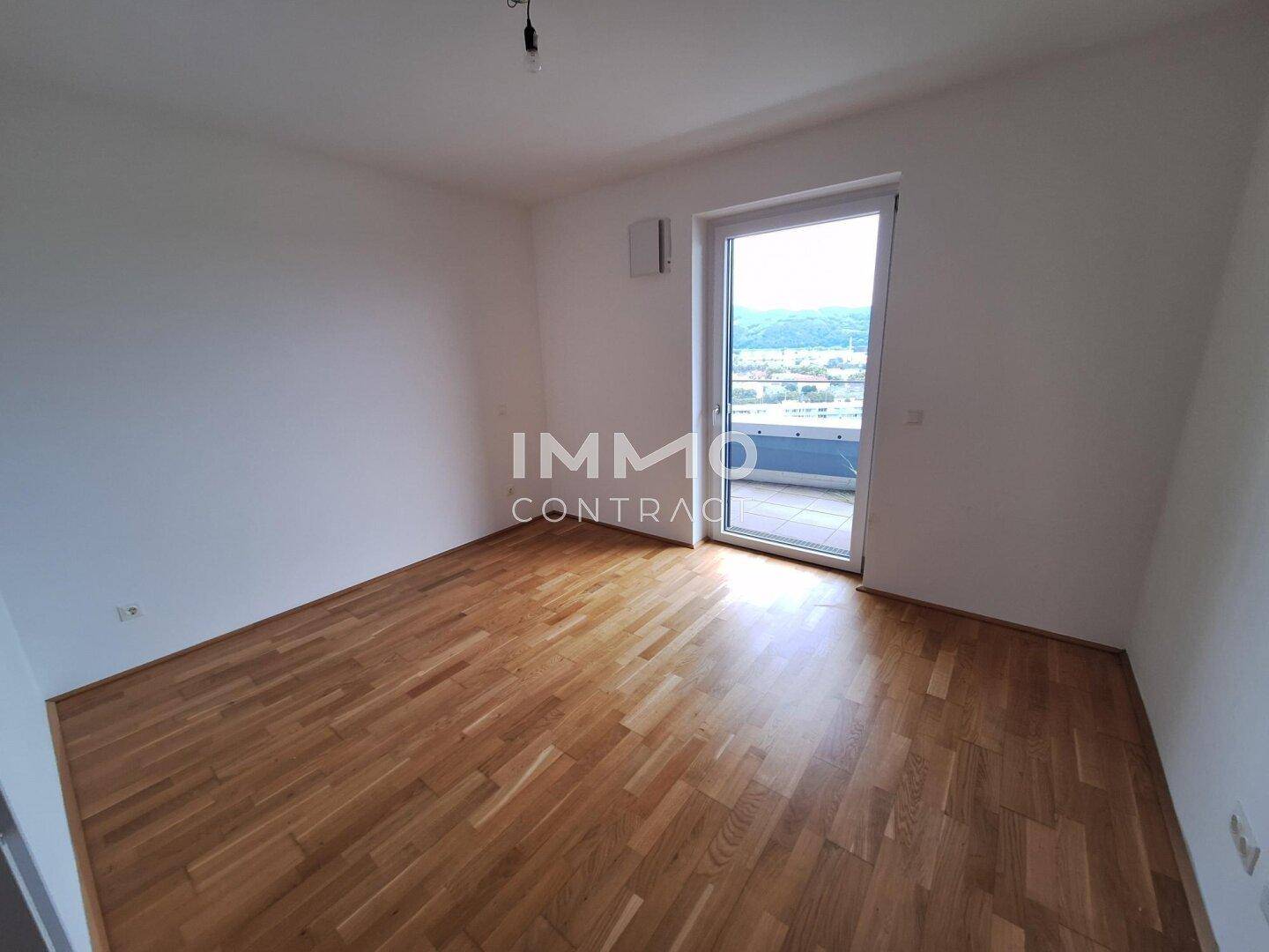 Helles Schlafzimmer mit Parkettboden und direktem Zugang zum Außenbereich.