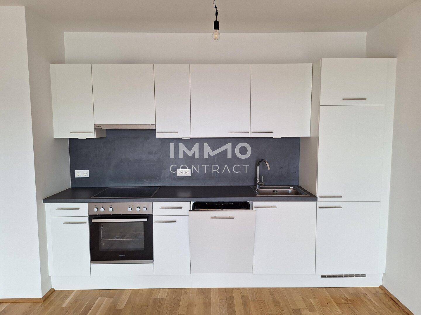 Moderne Einbauküche mit weißen Schränken, dunkler Arbeitsplatte und integrierten Geräten.