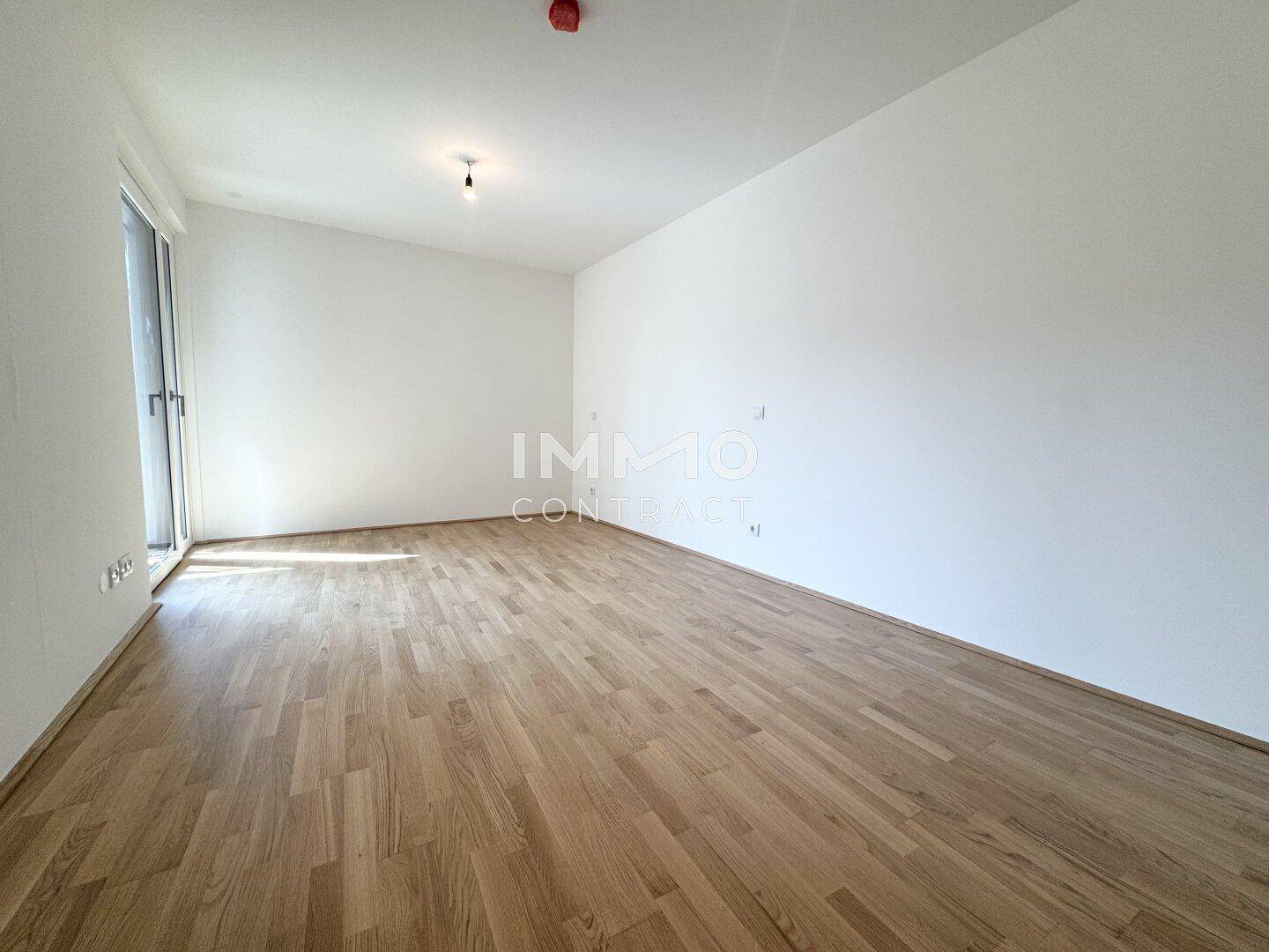 Helles, leeres Zimmer mit Parkettboden und weißen Wänden, bereit zur individuellen Gestaltung.