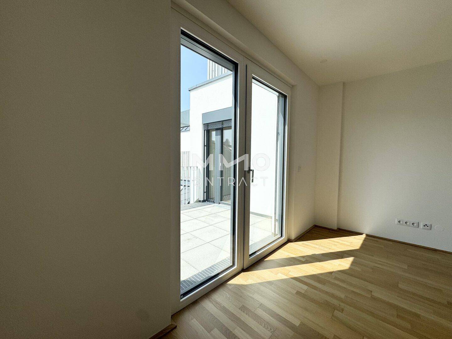 Heller Raum mit Parkettboden und großem Zugang zur Terrasse, ideal für viel Tageslicht.