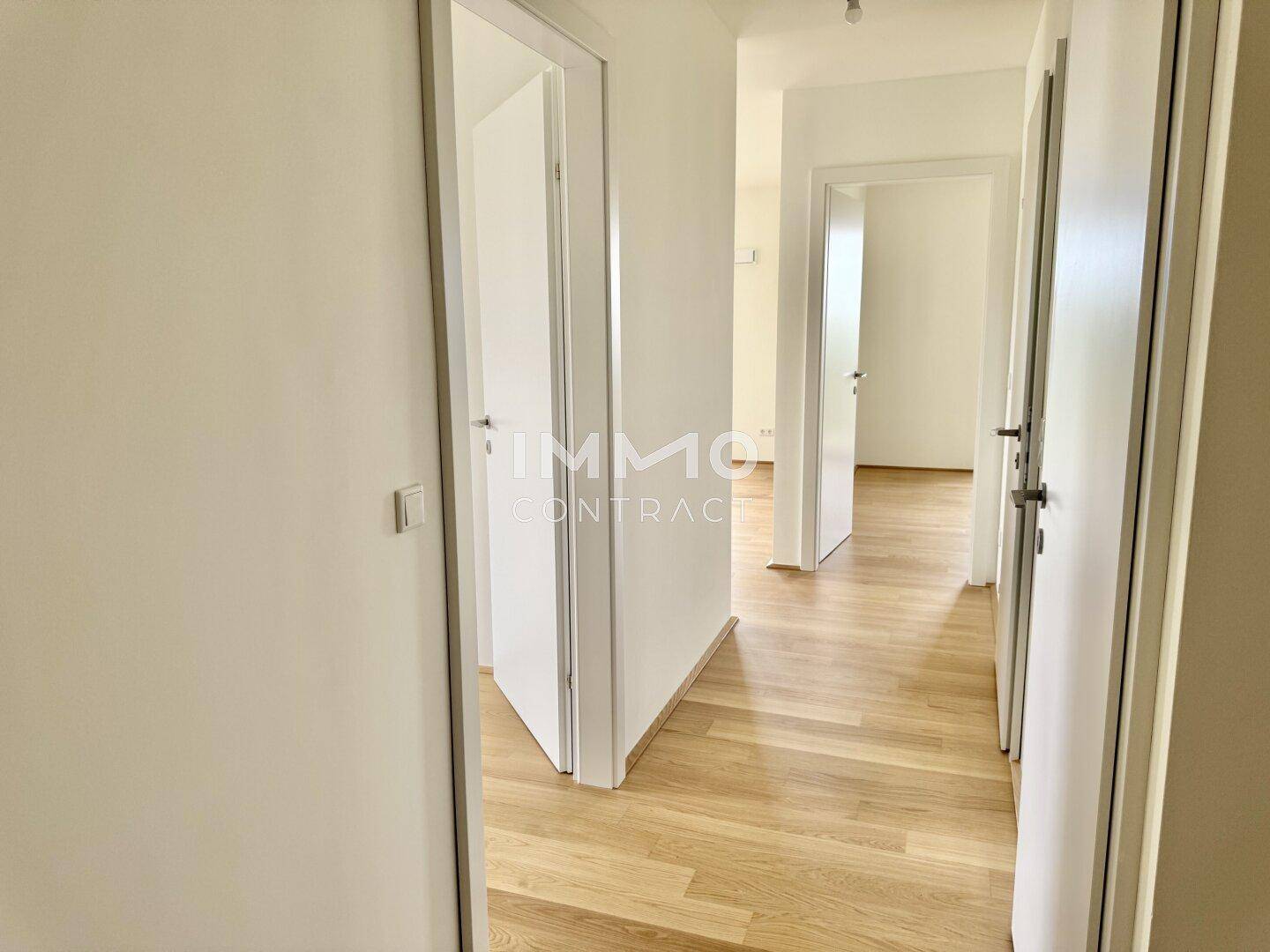 Heller Flur mit Holzboden und mehreren Türen, der verschiedene Räume miteinander verbindet.