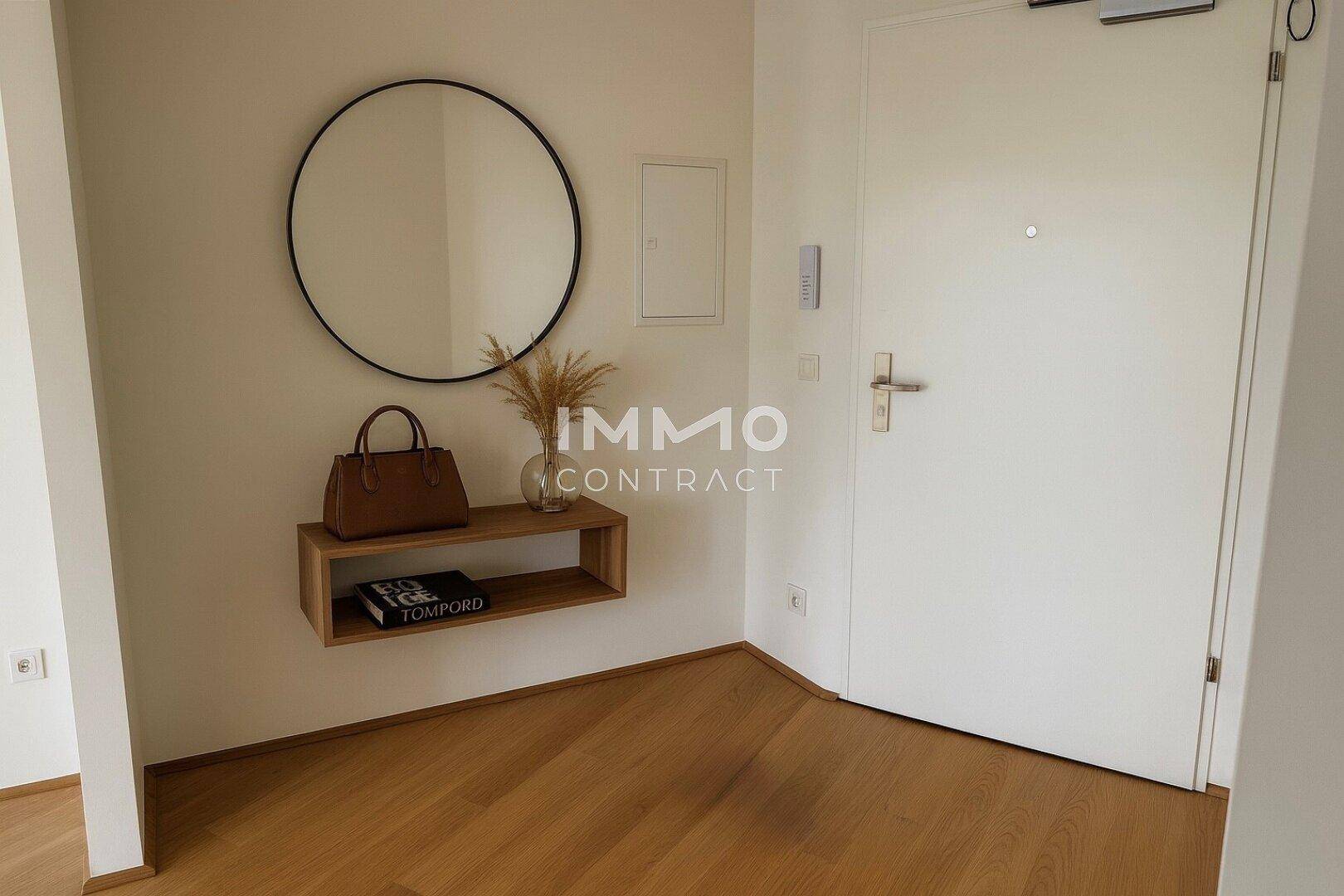 Heller Eingangsbereich mit Holzfußboden, einem runden Spiegel und einer schwebenden Ablage.