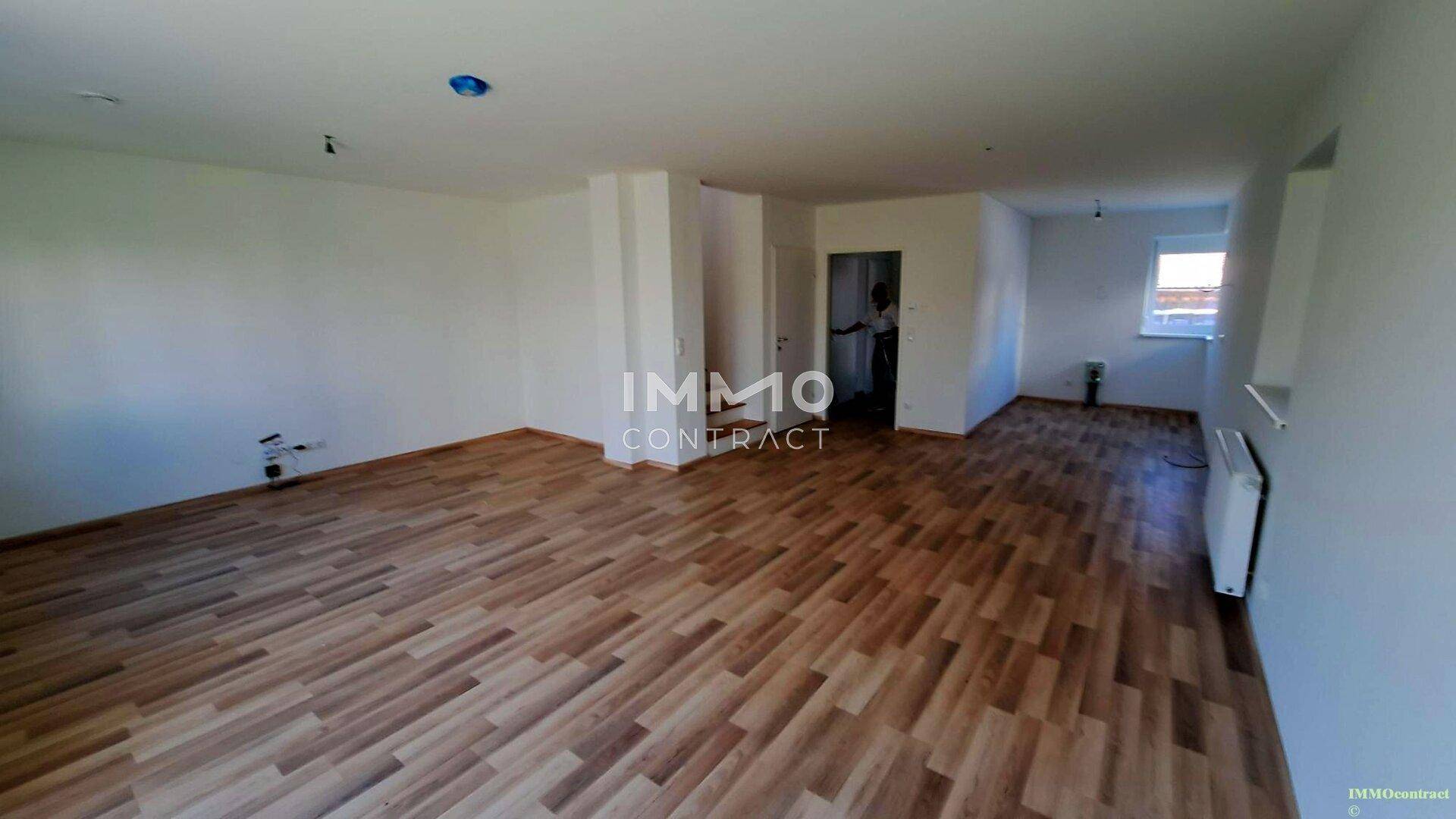 Geräumiger, heller Wohnbereich mit Laminatboden und viel Platz für Möbel.