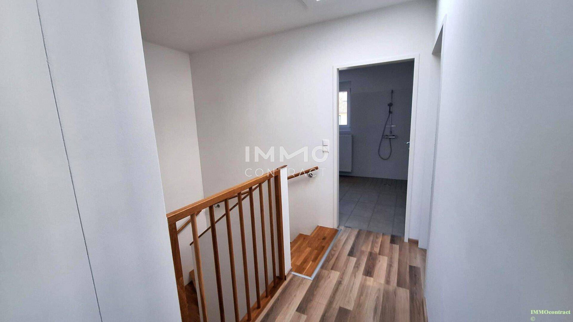 Heller Flur mit Holztreppe und Zugang zu weiteren Räumen im Obergeschoss.