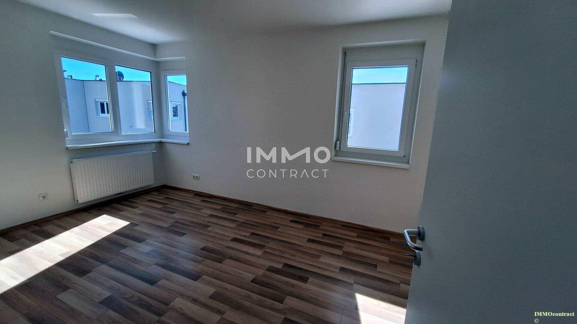 Geräumiges Schlafzimmer mit viel Tageslicht und modernem Laminatboden.