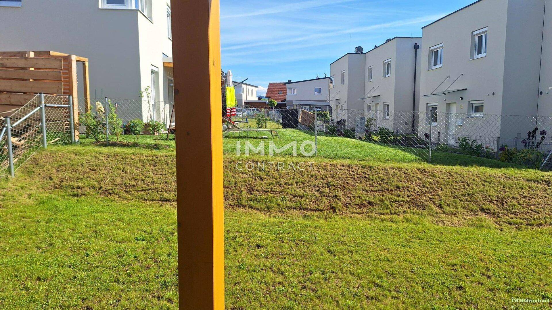 Gepflegter Rasenbereich im Garten mit Blick auf benachbarte Häuser in einer Wohnsiedlung.