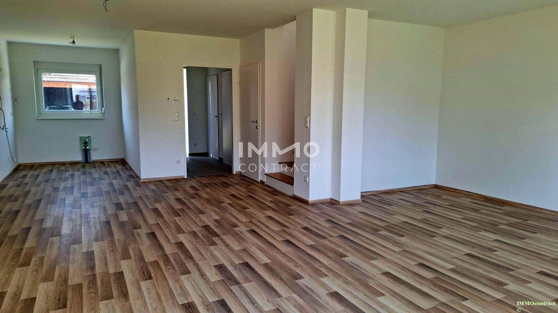 Heller Raum mit Laminatboden und Zugang zu weiteren Bereichen des Hauses.